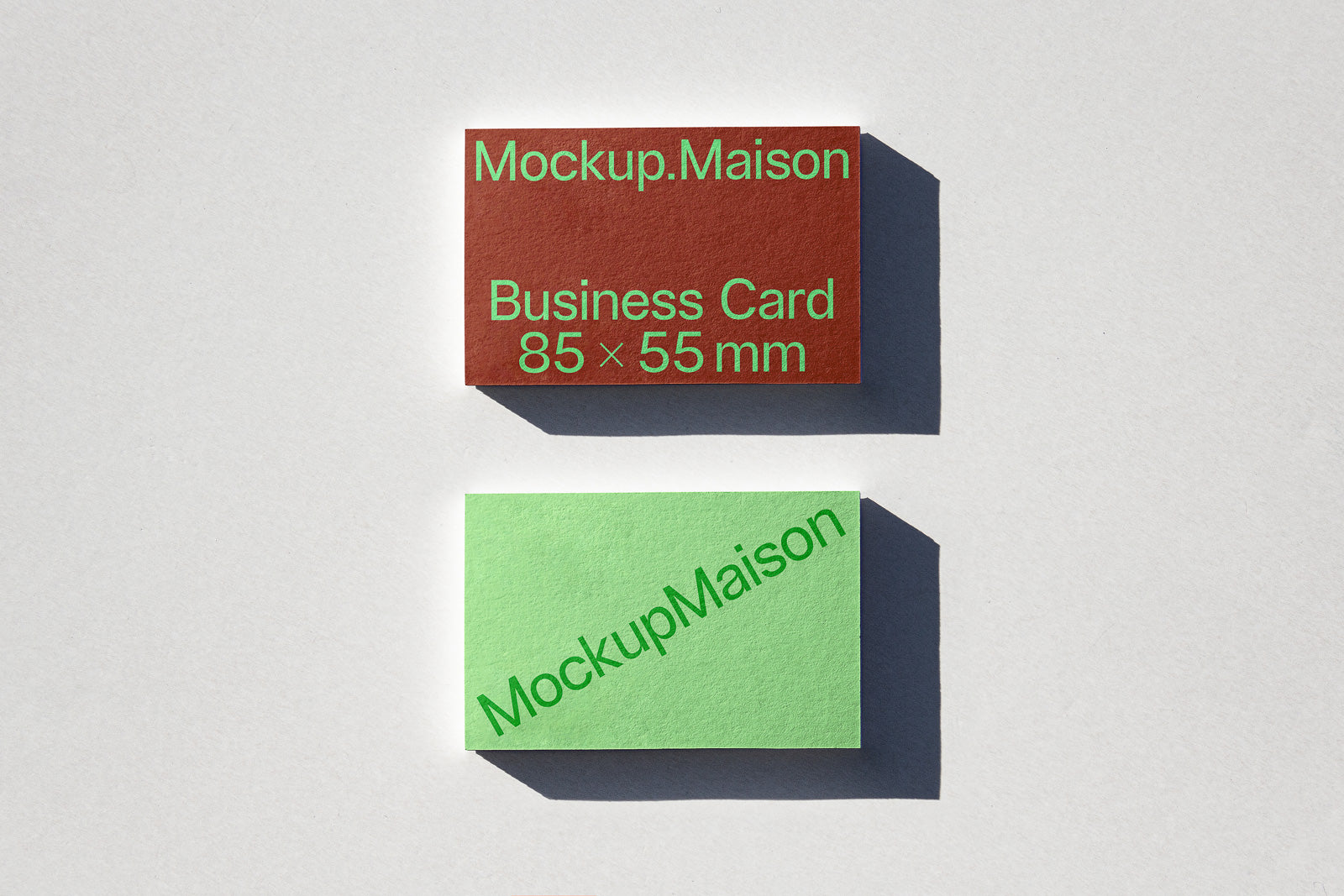 PSD mockup of two business cards on a light background, featuring a red card labeled "Mockup.Maison, Business Card 85 × 55 mm" and a green card labeled "MockupMaison".