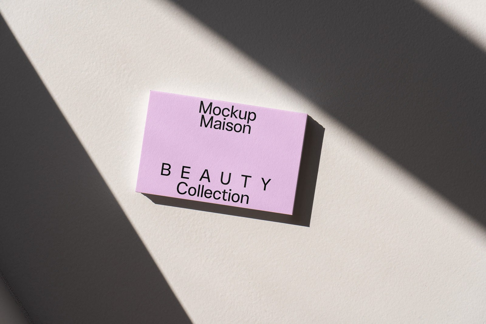 PSD mockup of a pink card labeled "Mockup Maison" and "BEAUTY Collection" with shadows on a light surface.