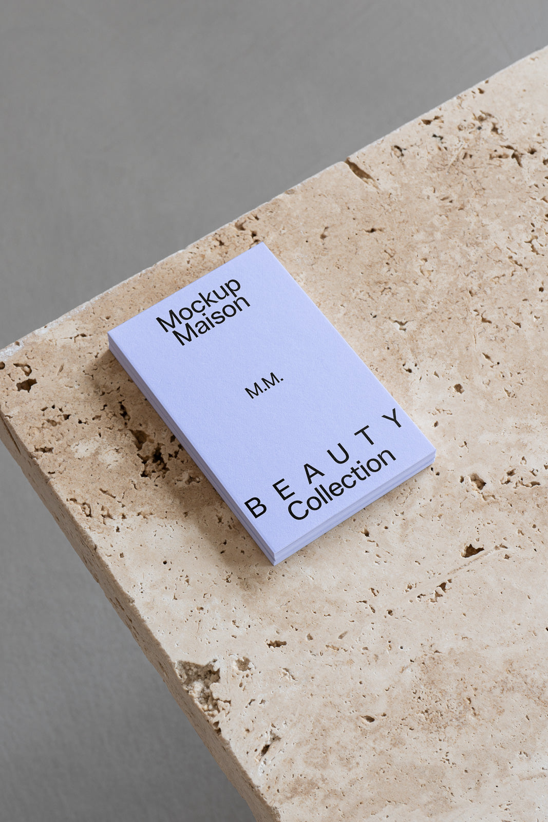 PSD mockup of a minimalist white booklet labeled "Mockup Maison Beauty Collection" placed on a textured stone surface, showcasing its clean design.