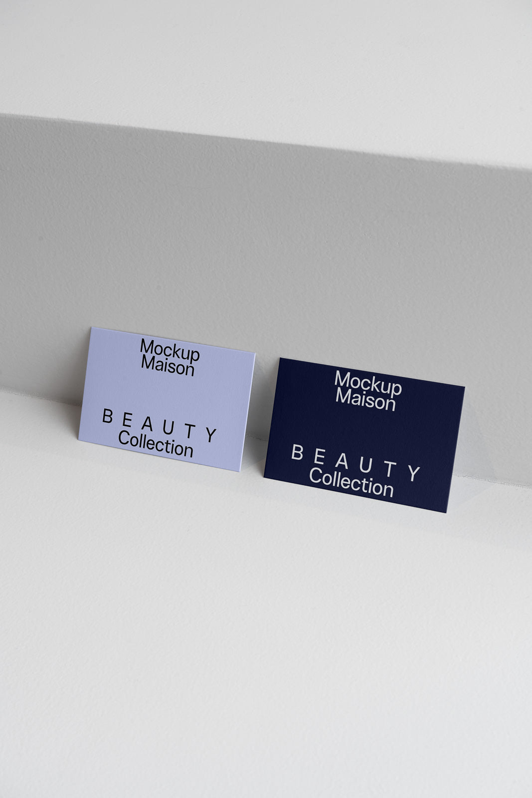 PSD mockup of two business cards labeled "Mockup Maison Beauty Collection" in light and dark tones, positioned on a white surface.