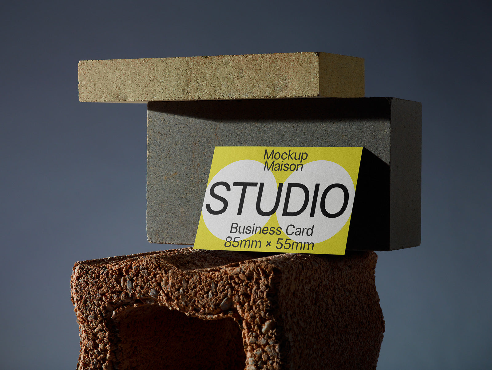 PSD mockup of a business card labeled "STUDIO" positioned on stacked bricks, highlighting card dimensions 85mm x 55mm.