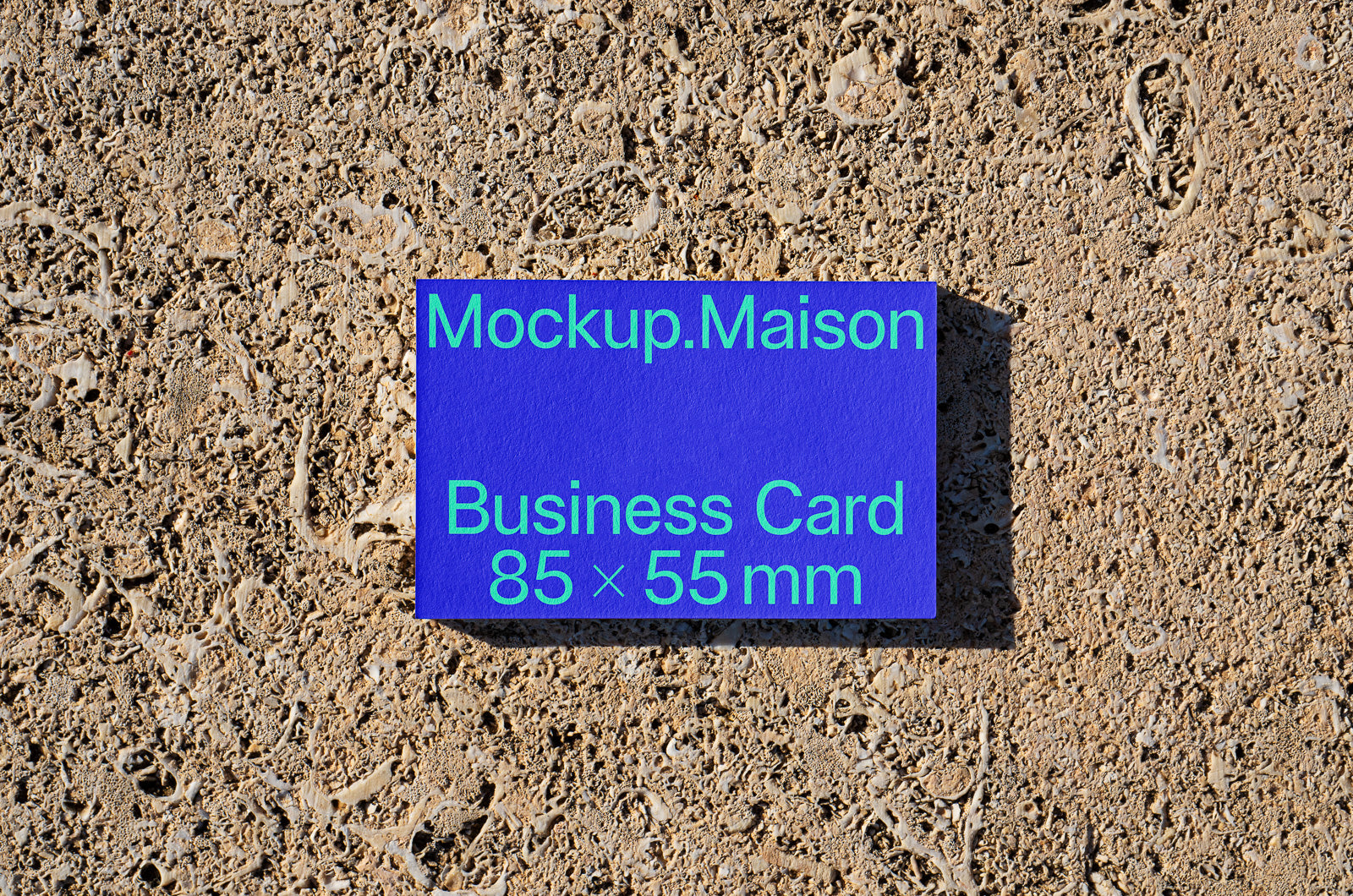 PSD mockup of a blue business card measuring 85 x 55 mm, placed on a textured stone surface, with text reading "Mockup.Maison Business Card".