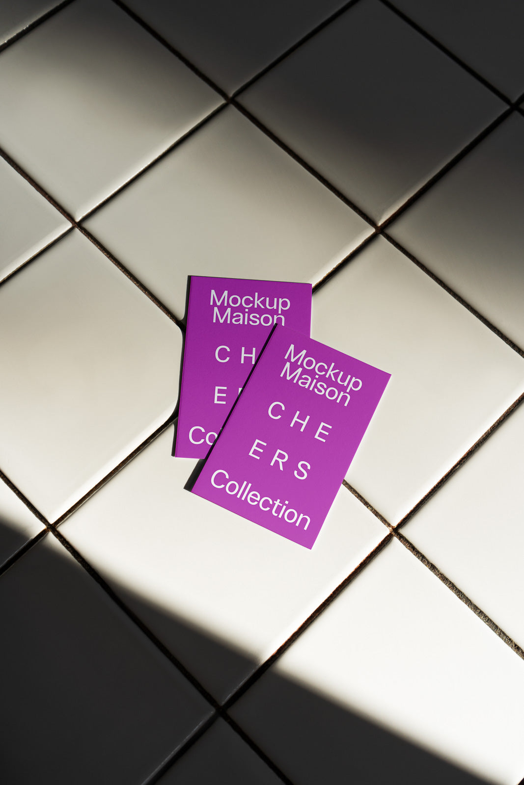 PSD mockup of two purple cards labeled "Mockup Maison Cheers Collection" placed on a tiled surface with diagonal lighting.