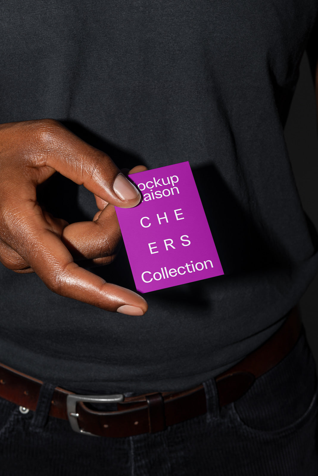 PSD mockup of a hand holding a purple card labeled "Mockup Maison CHEERS Collection" against a dark background.
