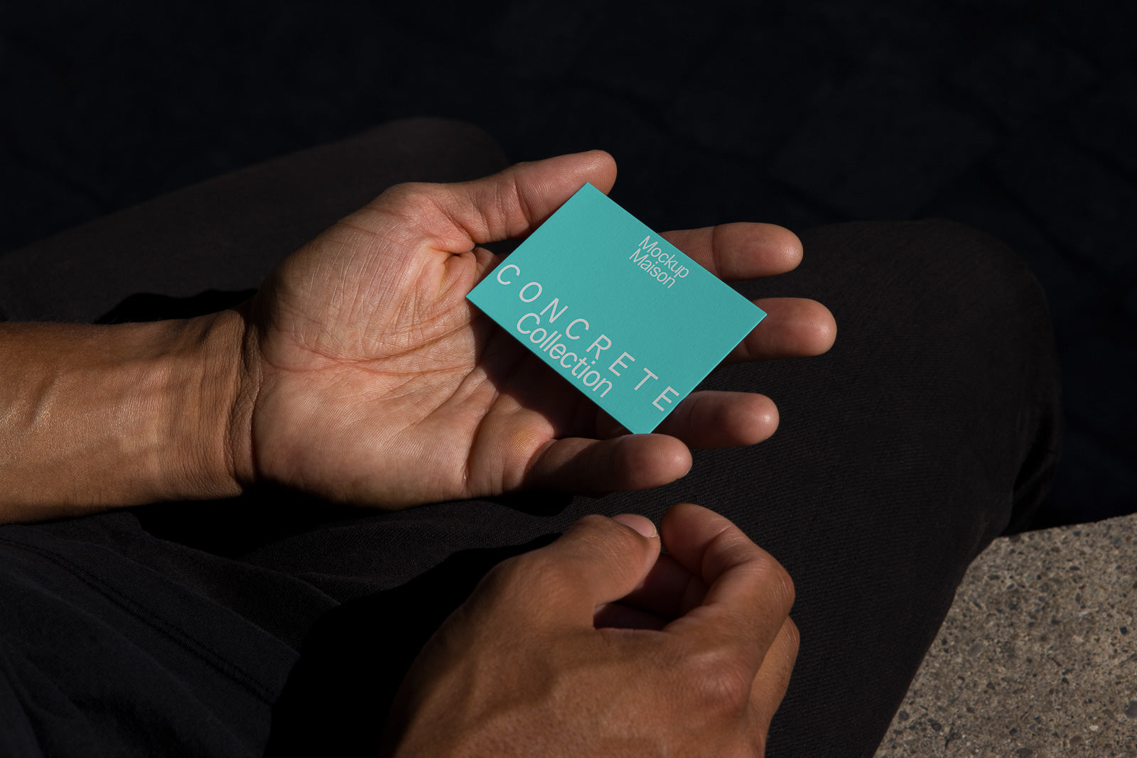 PSD mockup of a hand holding a turquoise card reading "Concrete Collection" and "Mockup Maison" on a dark background.