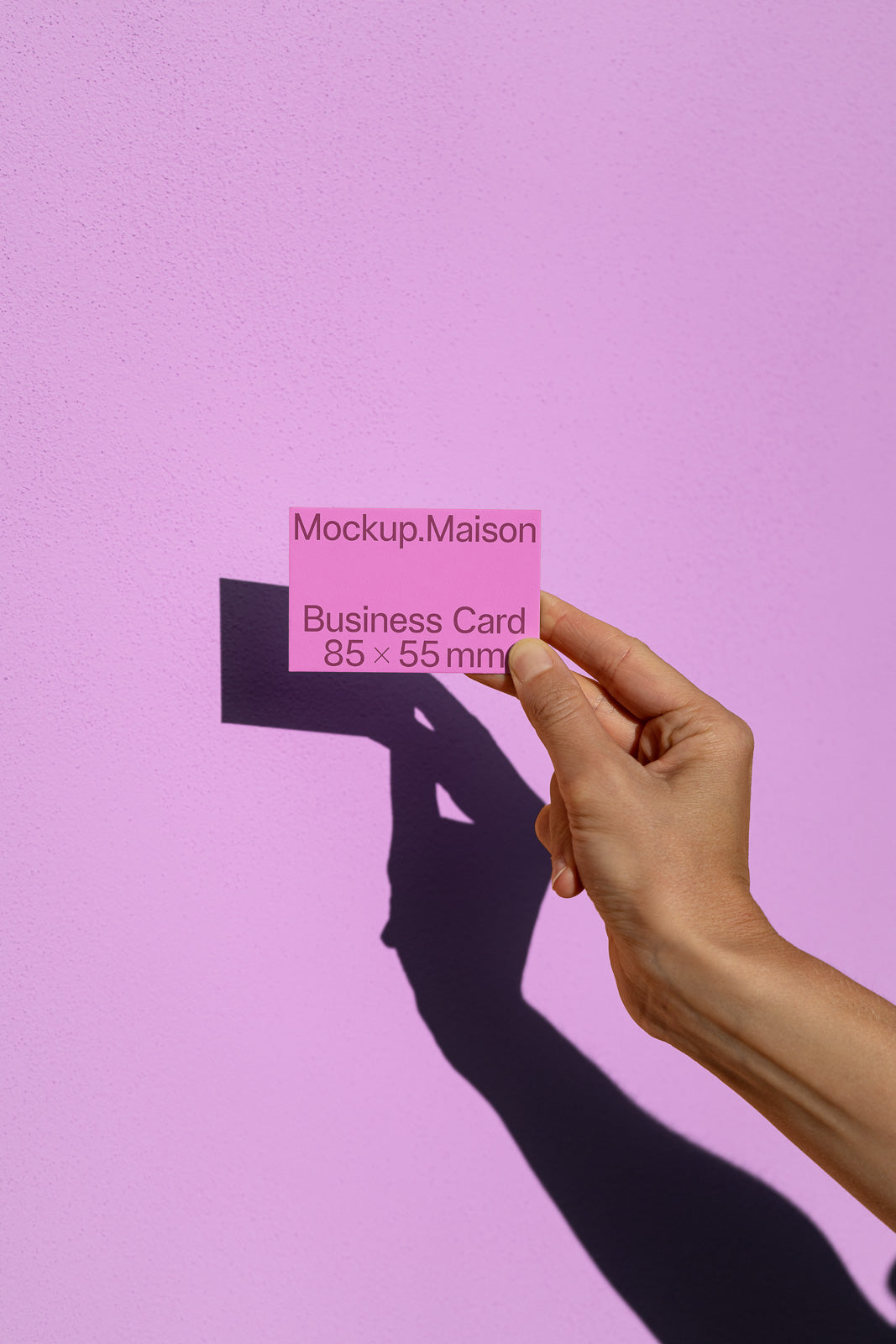 PSD mockup of a pink business card held by a hand against a matching pink background, with detailed dimensions and branding visible.
