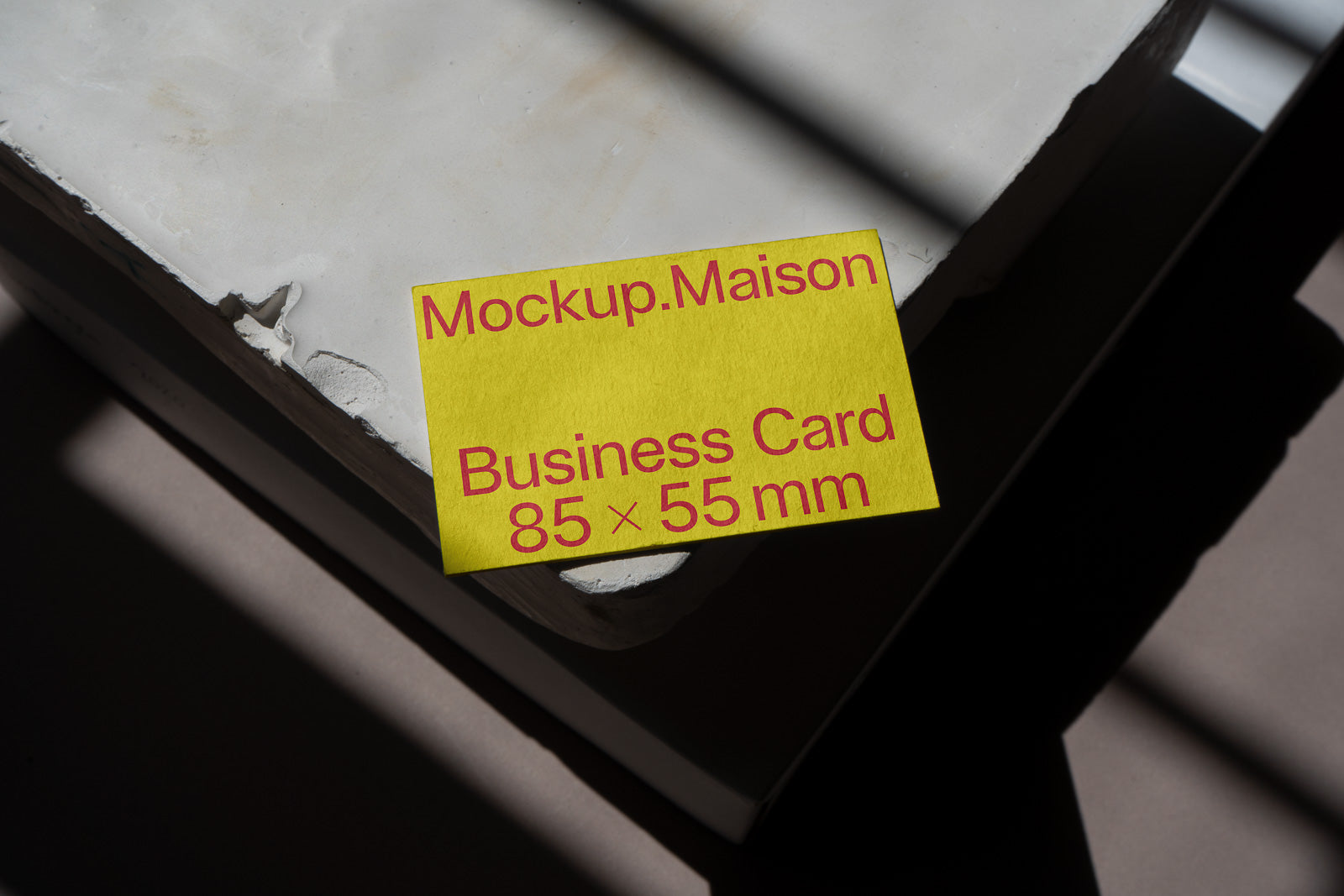 PSD mockup of a yellow business card labeled "Mockup.Maison" and "Business Card 85 × 55 mm" placed on a textured concrete surface.
