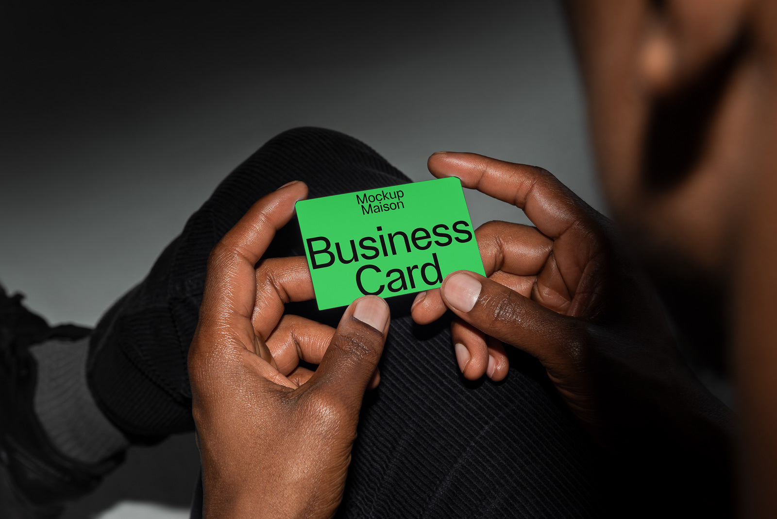 PSD mockup of a green business card held between fingers, displaying "Mockup Maison" and "Business Card" in bold black text.