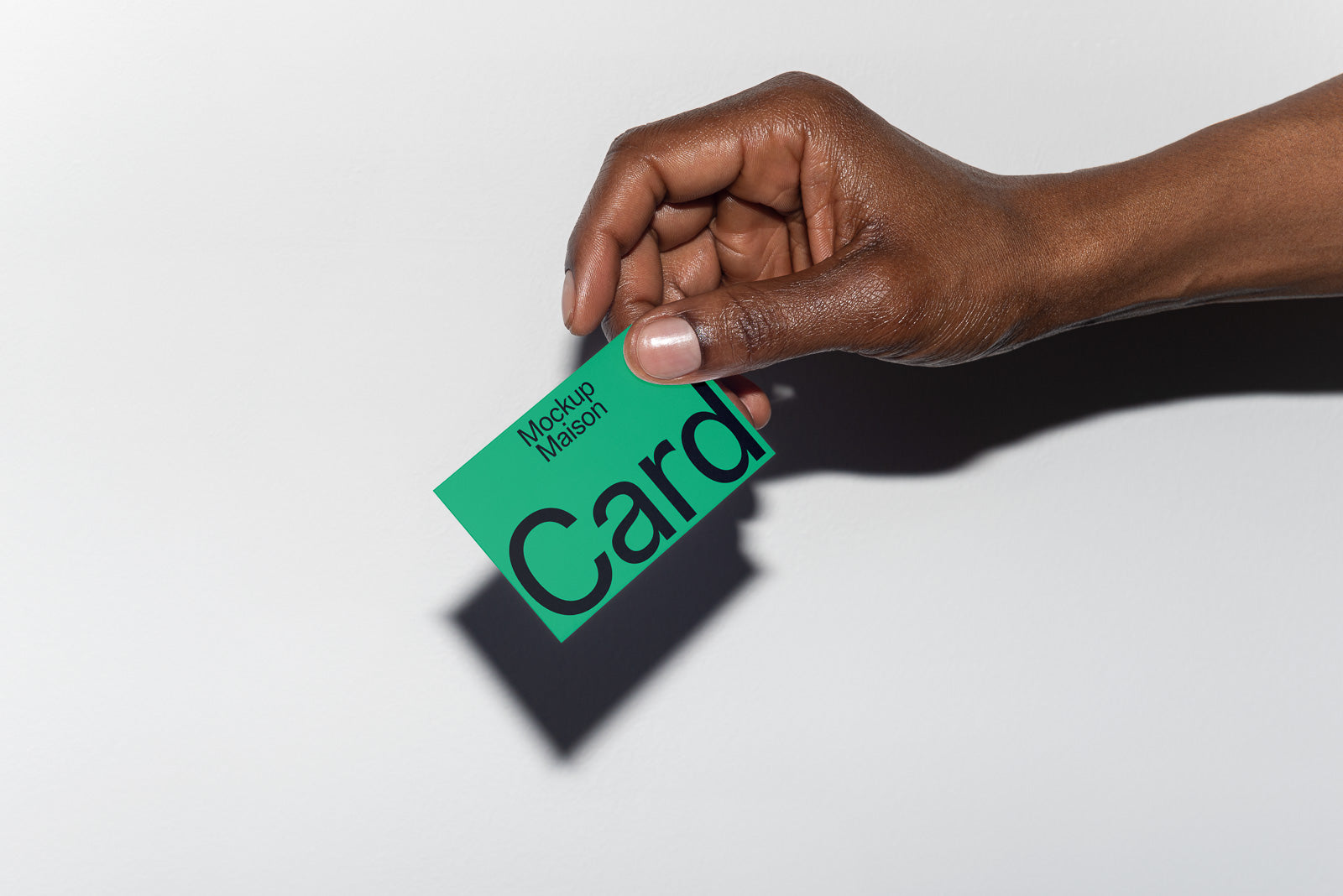 PSD mockup of a hand holding a green card with bold black text on a light gray background, highlighting the card's design and texture.