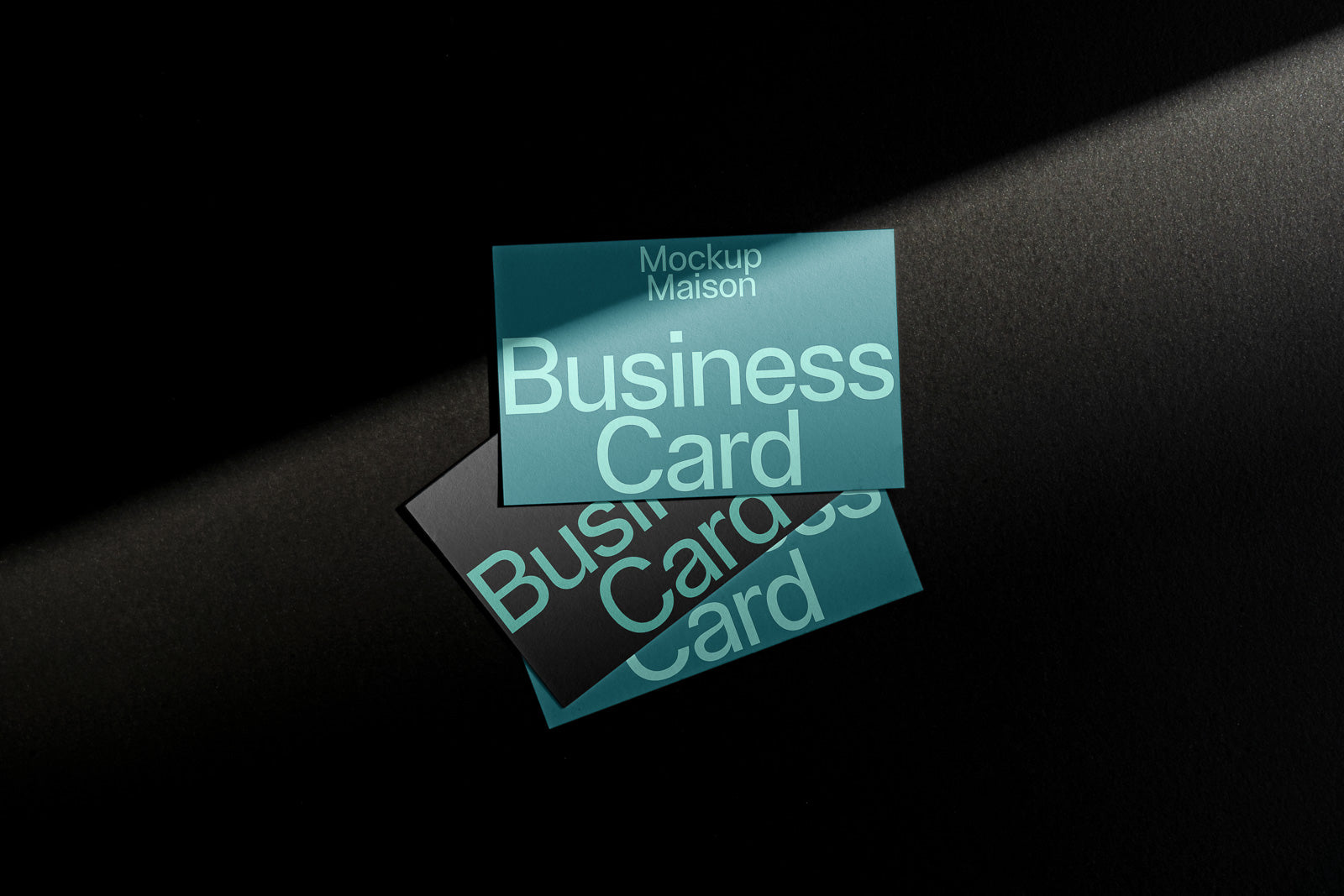 PSD mockup of two business cards on a dark surface, one card in turquoise with bold text partially shadowed, emphasizing design layout.