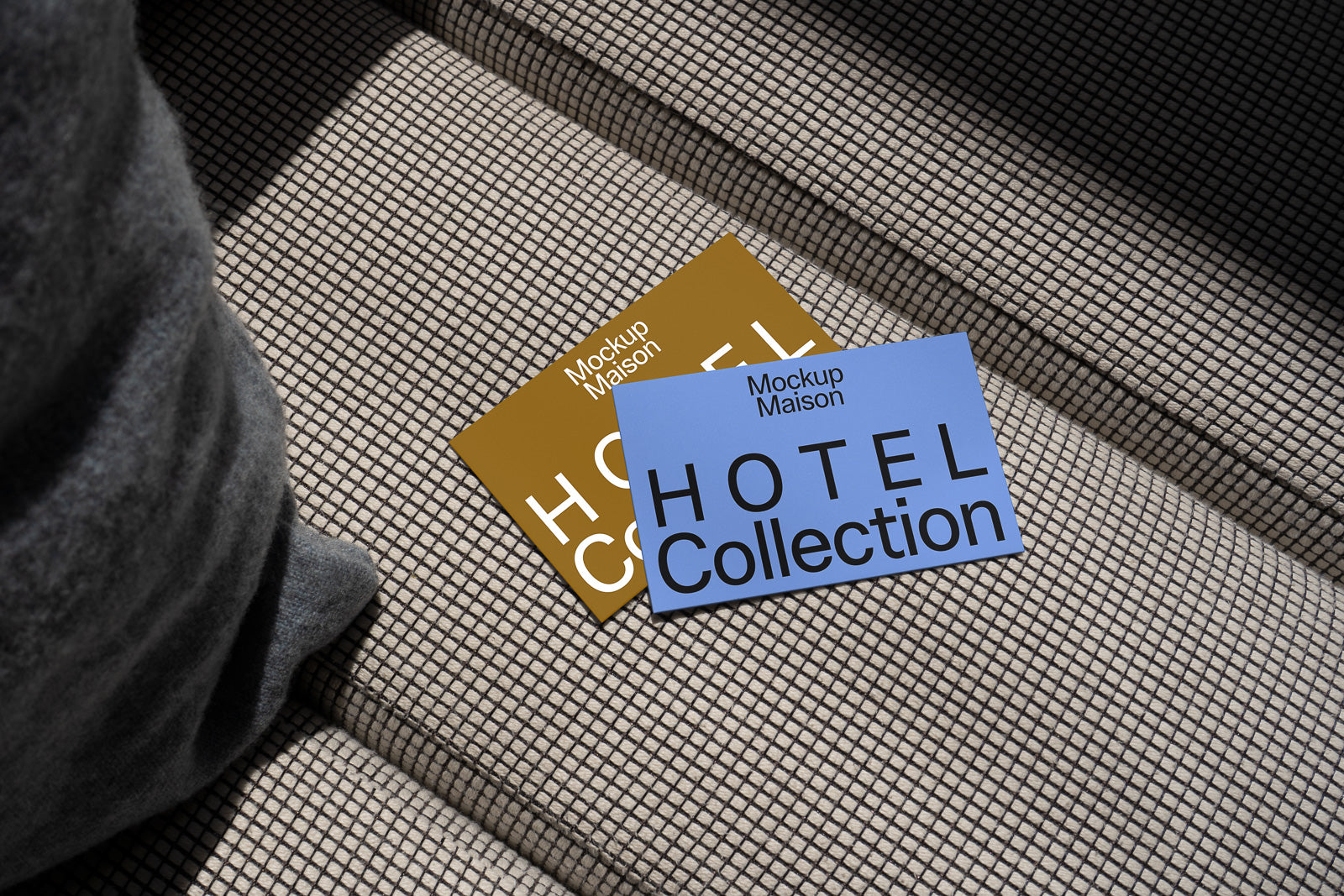 PSD mockup of two "Hotel Collection" cards, one blue and one gold, resting on a textured fabric surface with a grey cushion nearby.