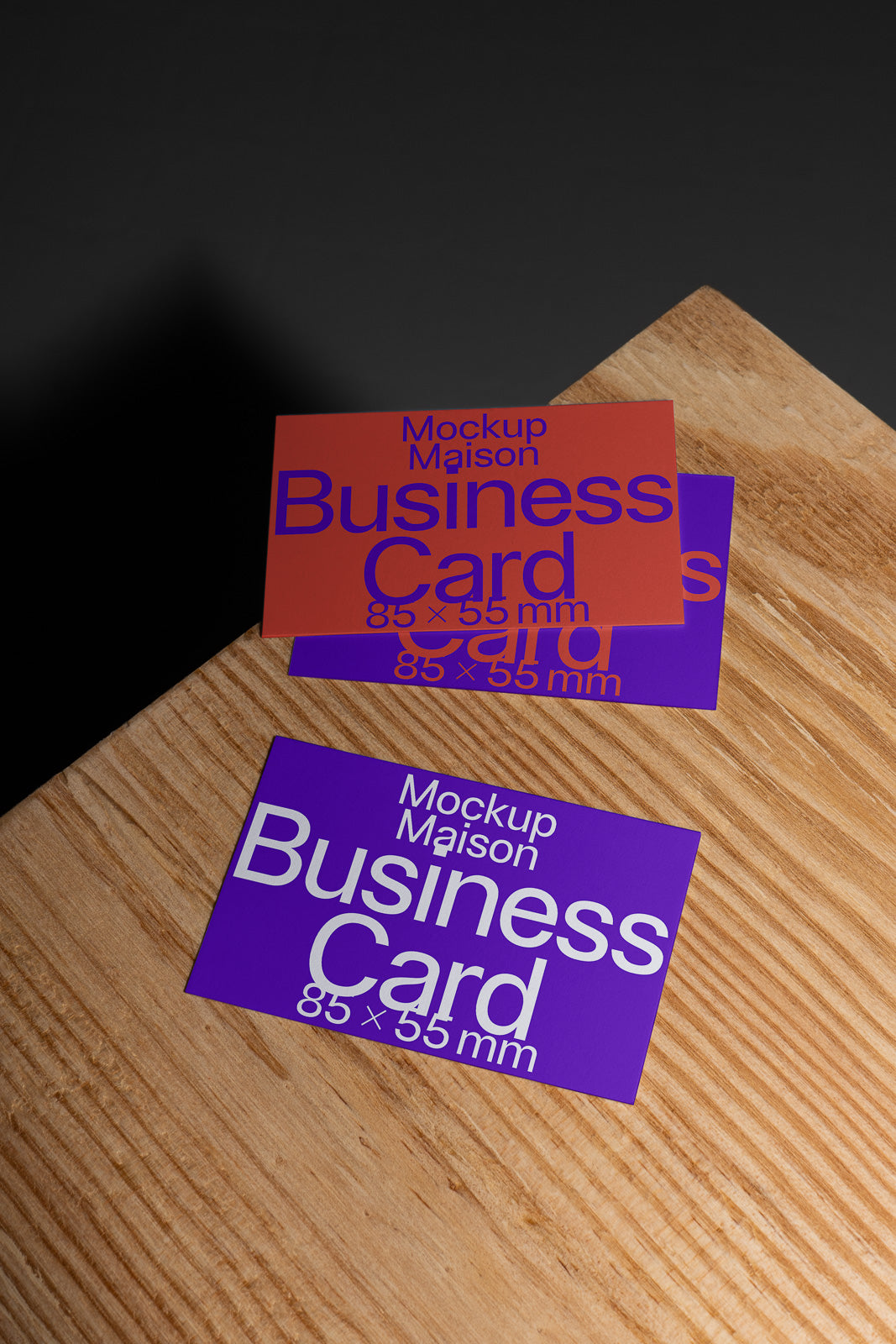 PSD mockup of two business cards on a wooden surface, displaying front and back designs with bold purple and orange colors in 85 x 55 mm size.