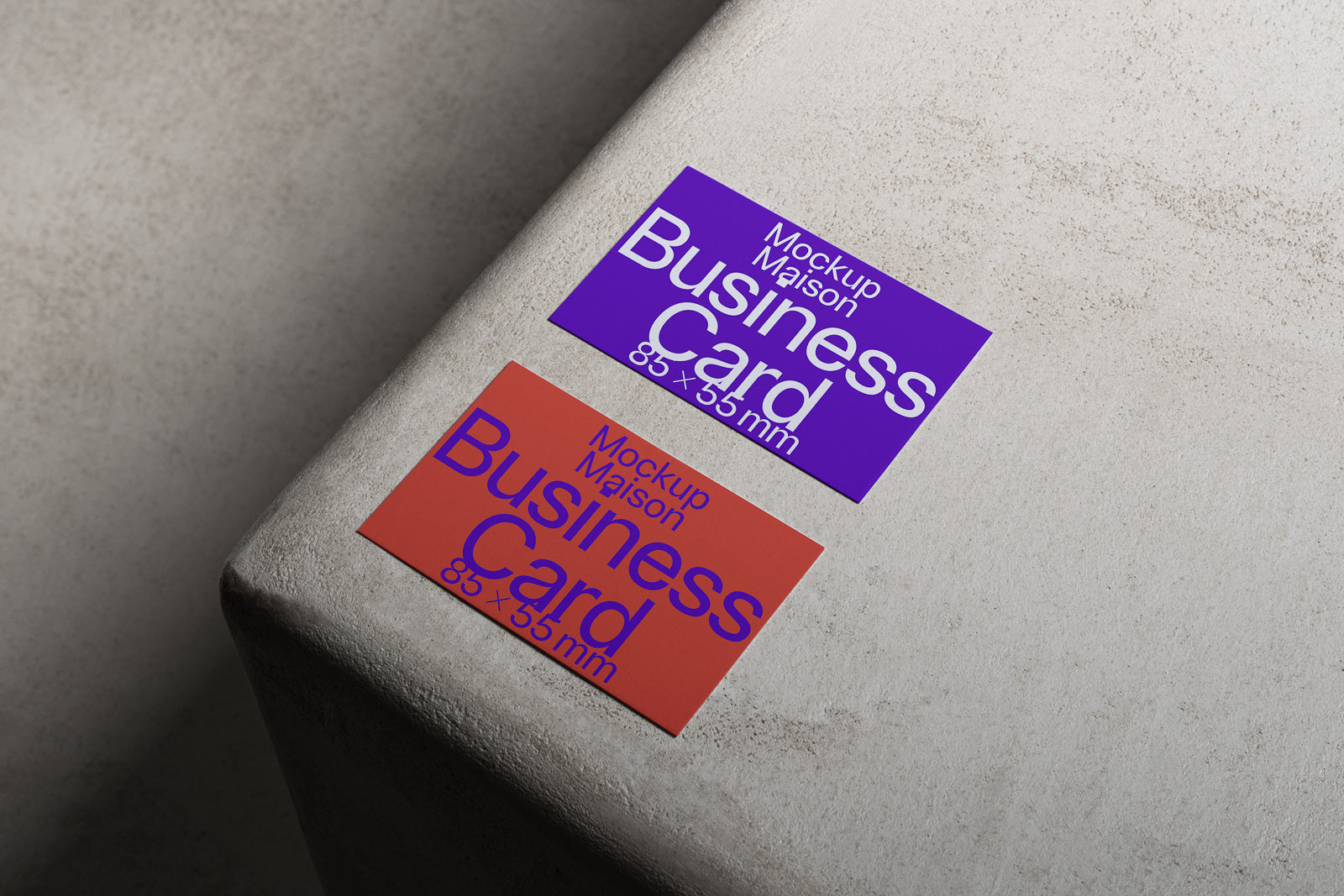 PSD mockup of two business cards on a textured surface; one card is purple, the other red, both with bold white text displaying dimensions 85 x 55 mm.
