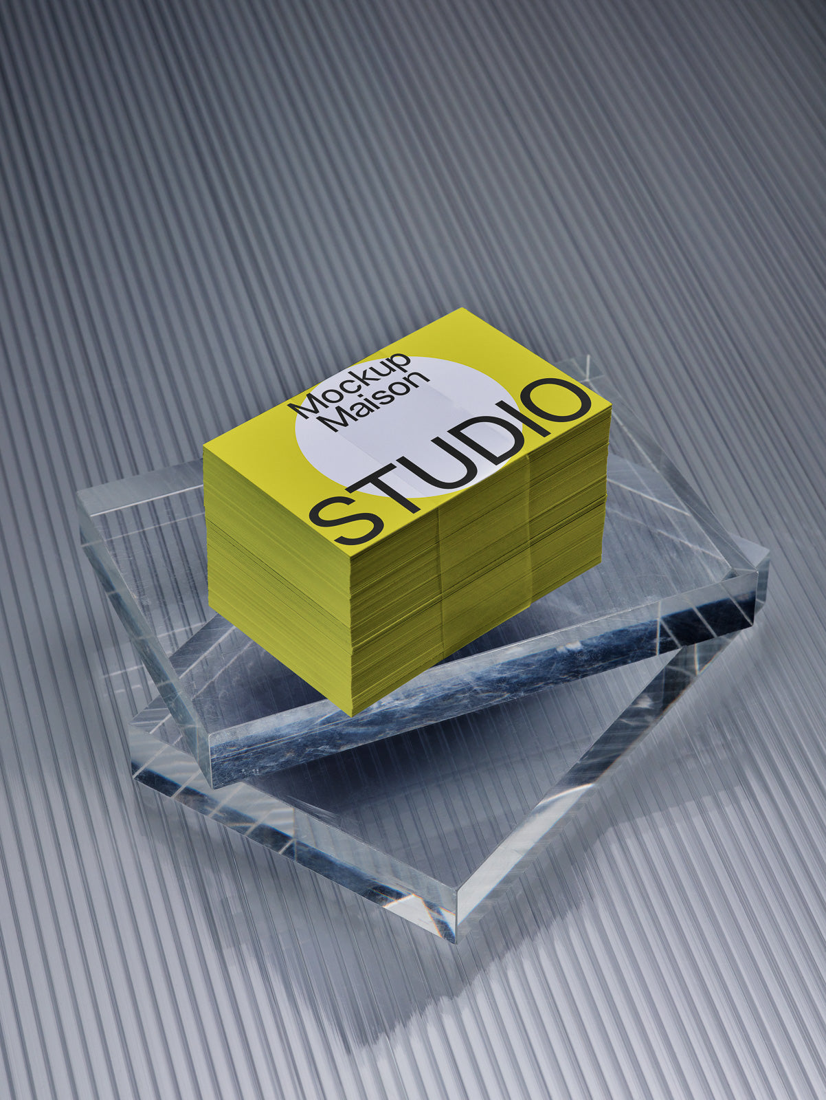 PSD mockup of a stack of yellow business cards with "Mockup Maison STUDIO" text, placed on a reflective surface with a textured background.