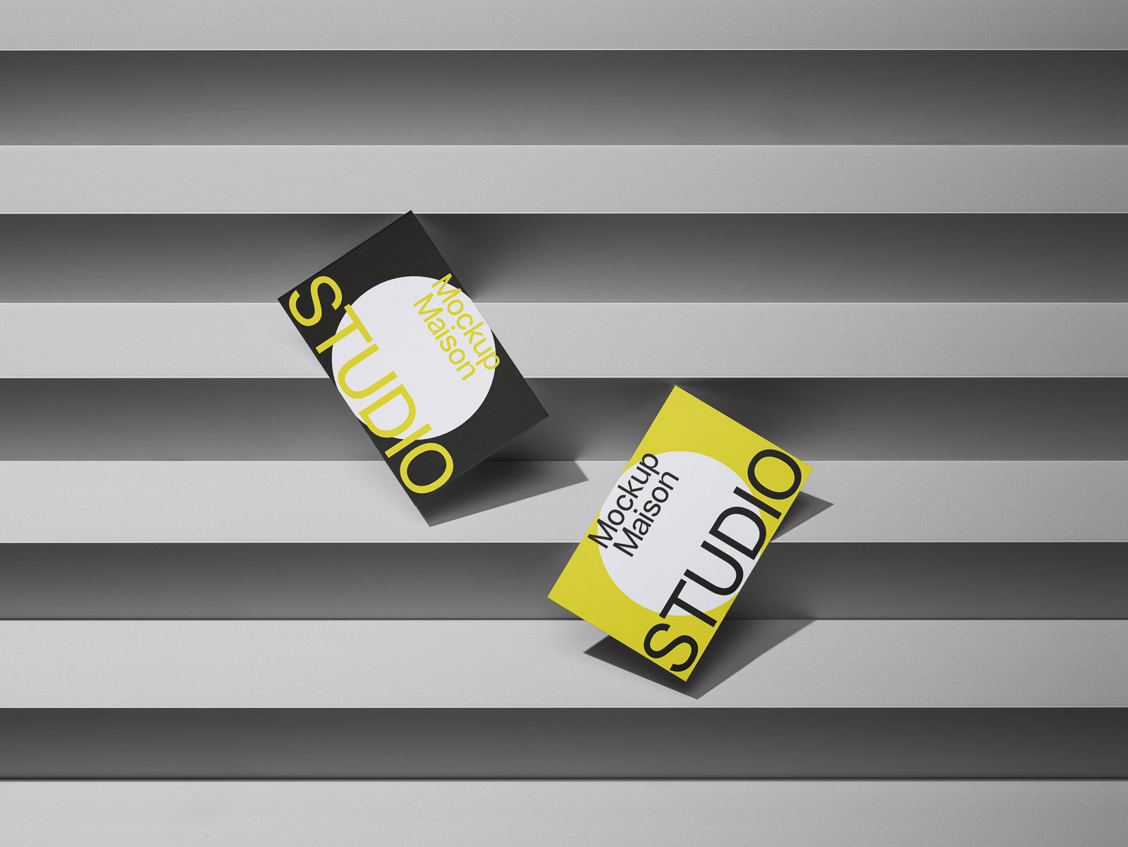 PSD mockup of two business cards, one black and one yellow, with "Studio" text, placed on gray horizontal surface with shadows.