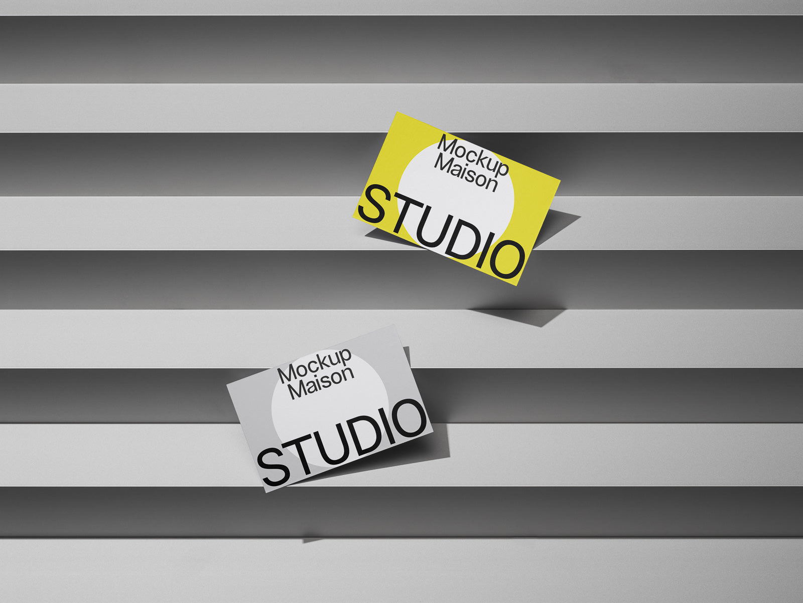 PSD mockup of two business cards positioned on a layered gray background, one card is yellow and the other white, both labeled "Mockup Maison Studio."
