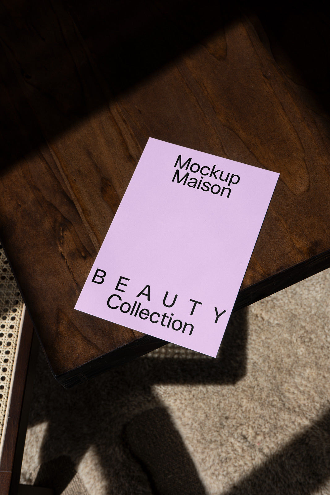 PSD mockup of a lilac flyer with "Mockup Maison Beauty Collection" text on a wooden surface in sunlight.