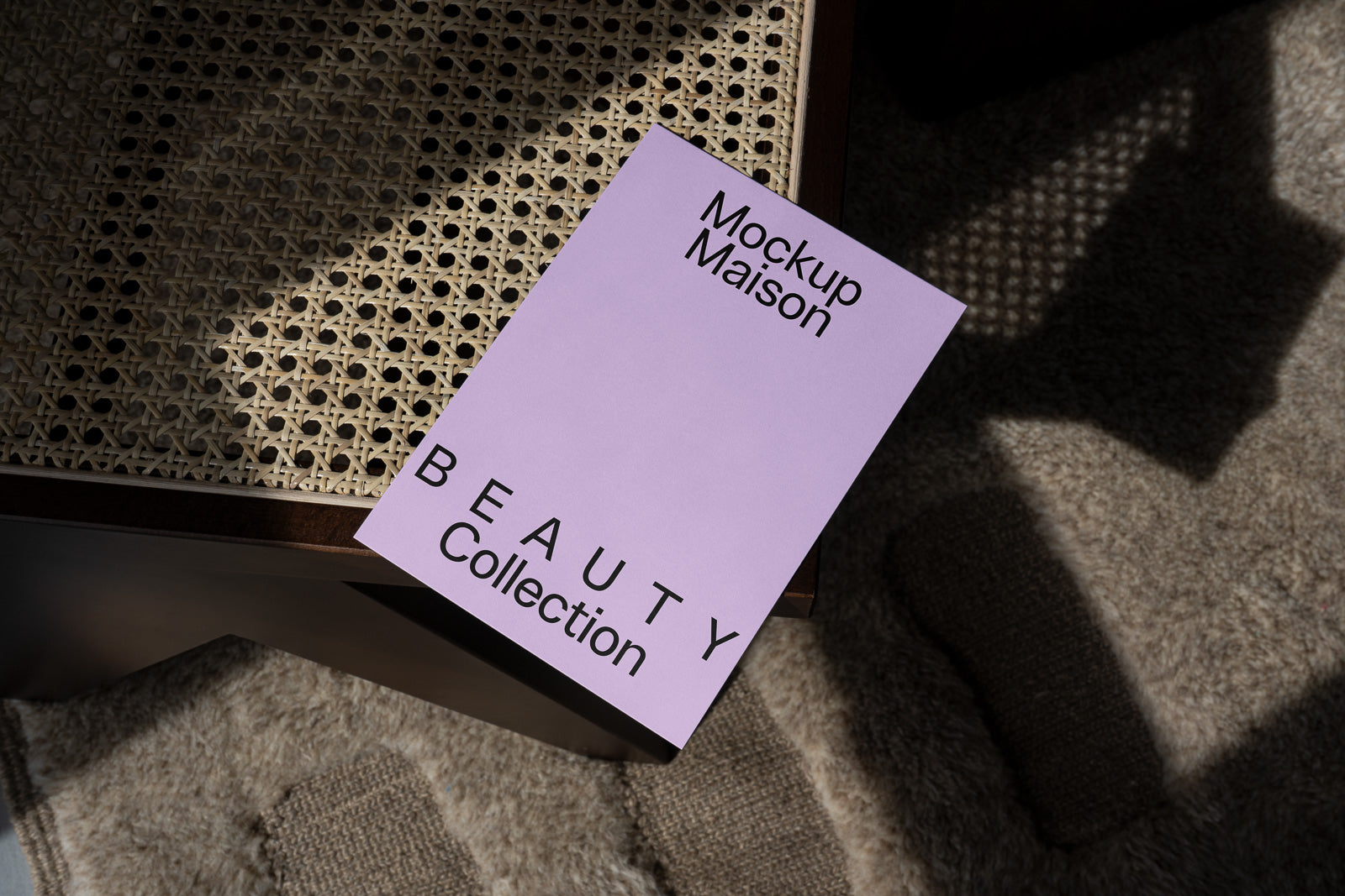 PSD mockup of a purple booklet titled "Mockup Maison, Beauty Collection" on a textured wicker surface and a woven rug.
