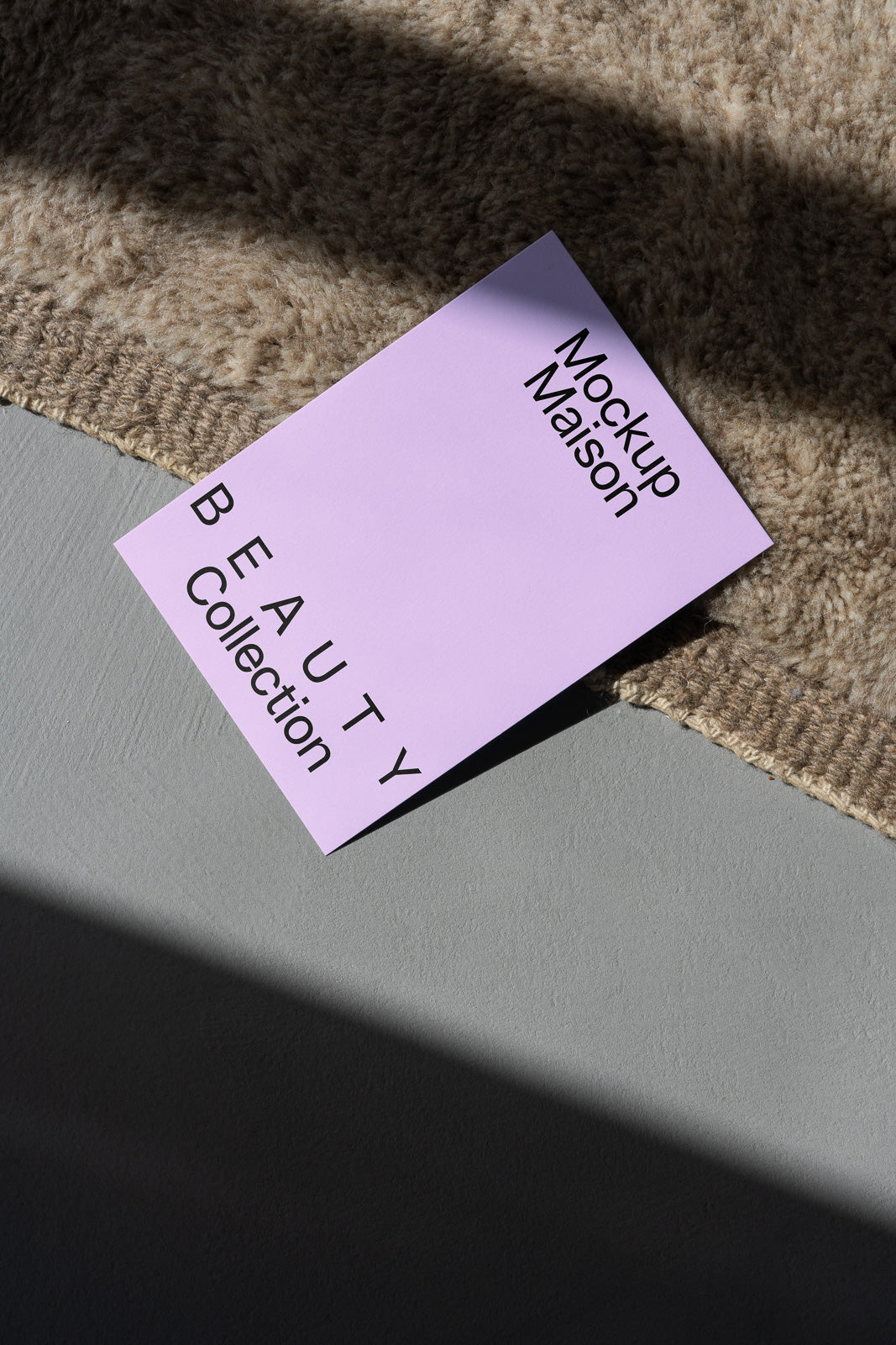 PSD mockup of a lavender card placed diagonally on a textured surface, displaying "Beauty Collection" and "Mockup Maison" in black text.