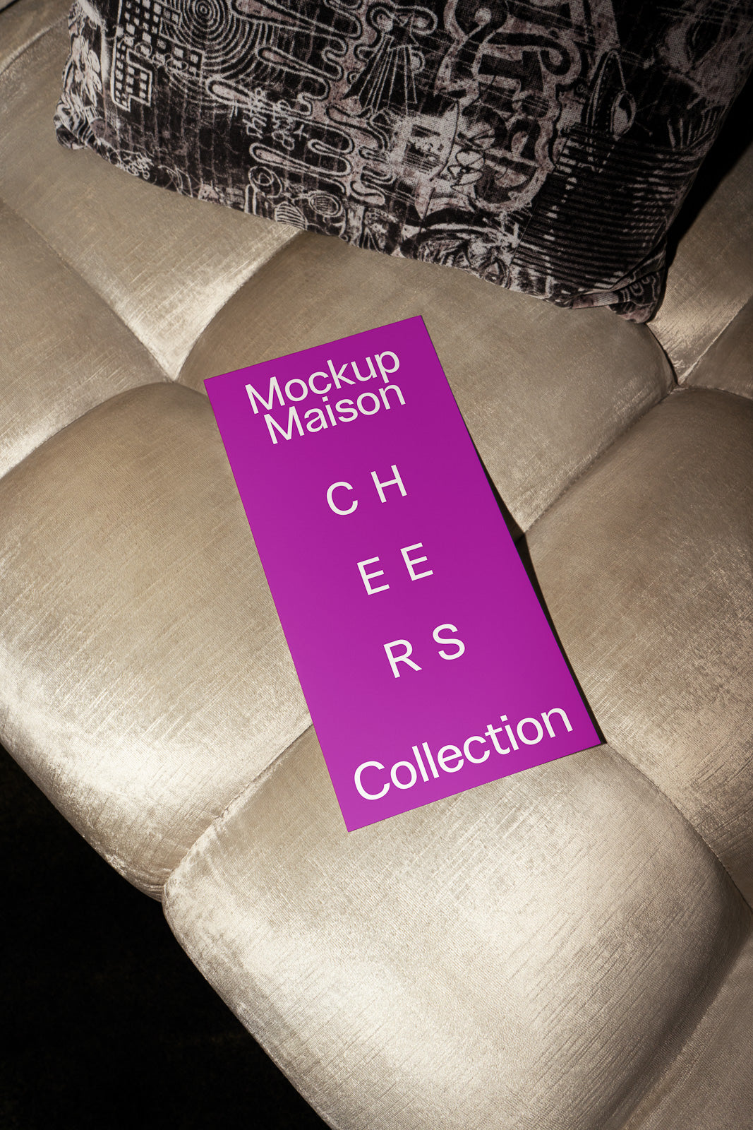 PSD mockup of a purple card labeled "Mockup Maison CHEERS Collection" placed on a beige cushioned surface with a patterned pillow.