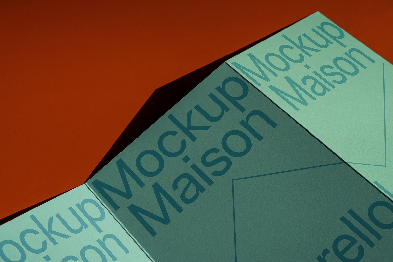 PSD mockup of a folded paper design, featuring the text "Mockup Maison" in large letters on a green background, set against an orange surface.