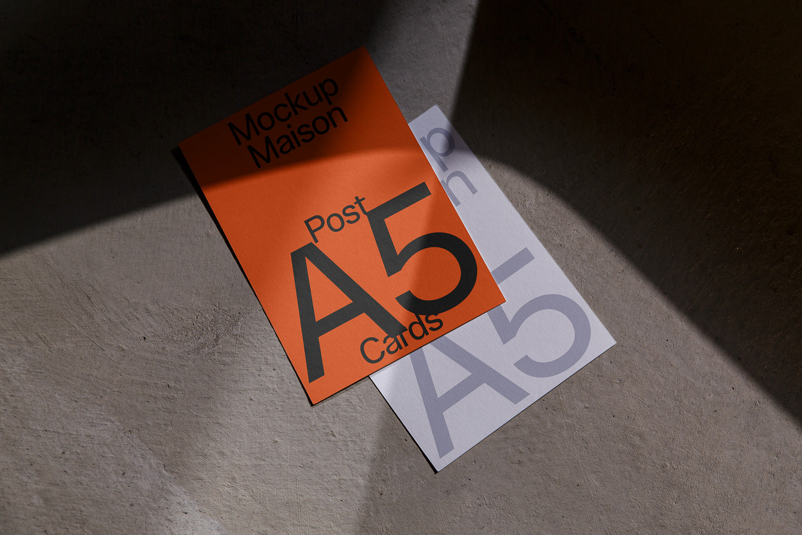 PSD mockup of two overlapping A5 cards on a textured surface, one orange with bold black text, the other white with subtle gray text.