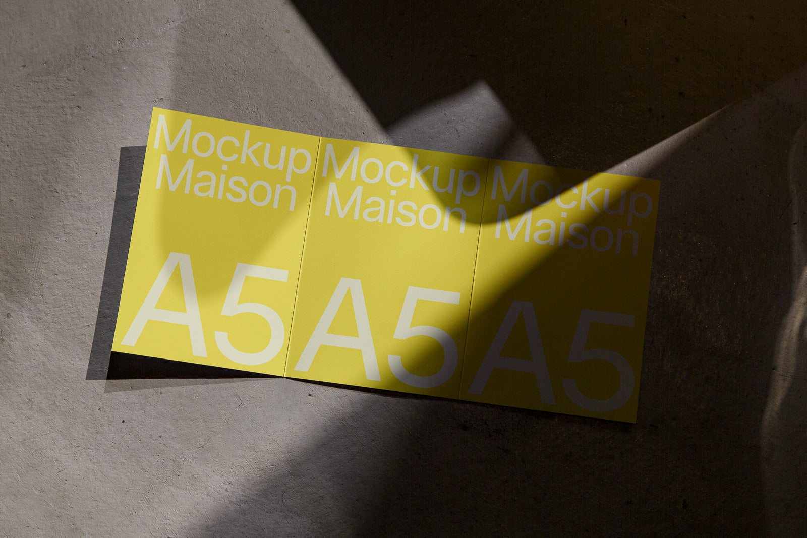 PSD mockup of three yellow A5 size cards placed on a textured surface, showcasing the text "Mockup Maison A5" with shadows cast across them.