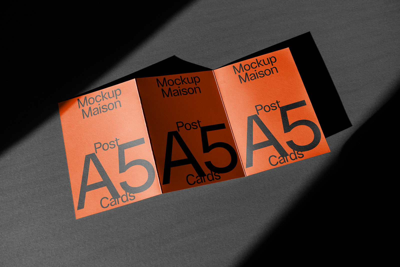 PSD mockup of three orange A5 post cards, lined up with bold black text displaying "Mockup Maison" and "Post A5 Cards" under a dramatic shadow.