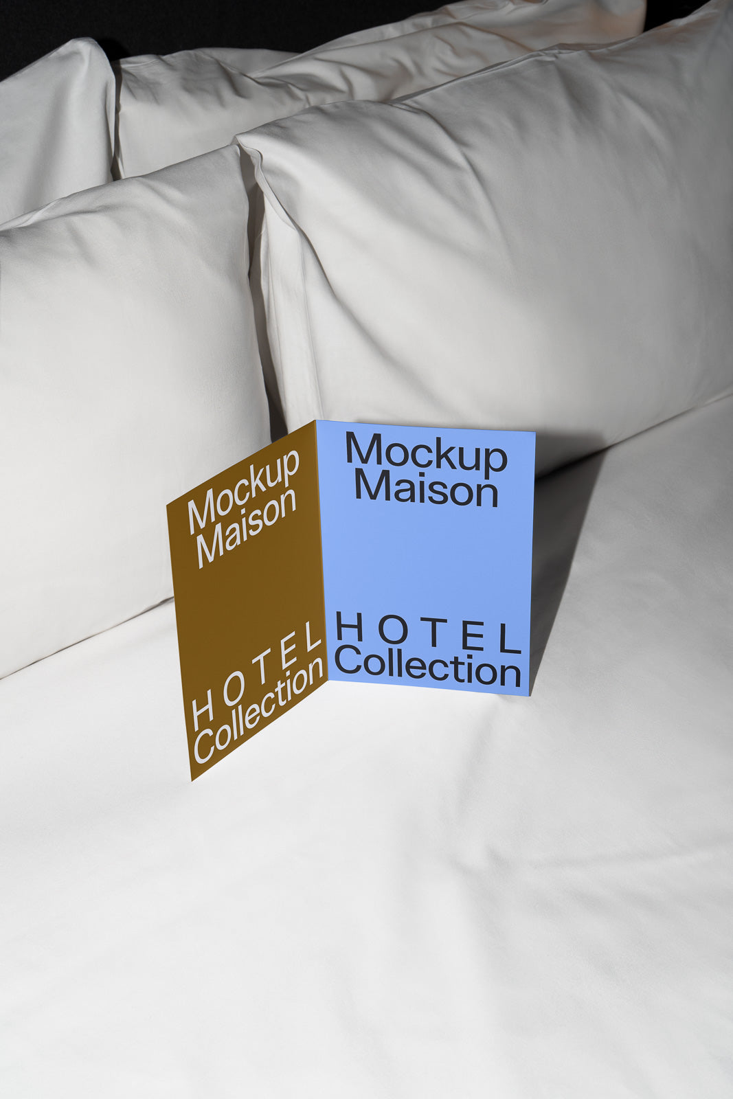 PSD mockup of a folded brochure on hotel bed linens, featuring "Mockup Maison" and "HOTEL Collection" text in brown and blue on a white background.