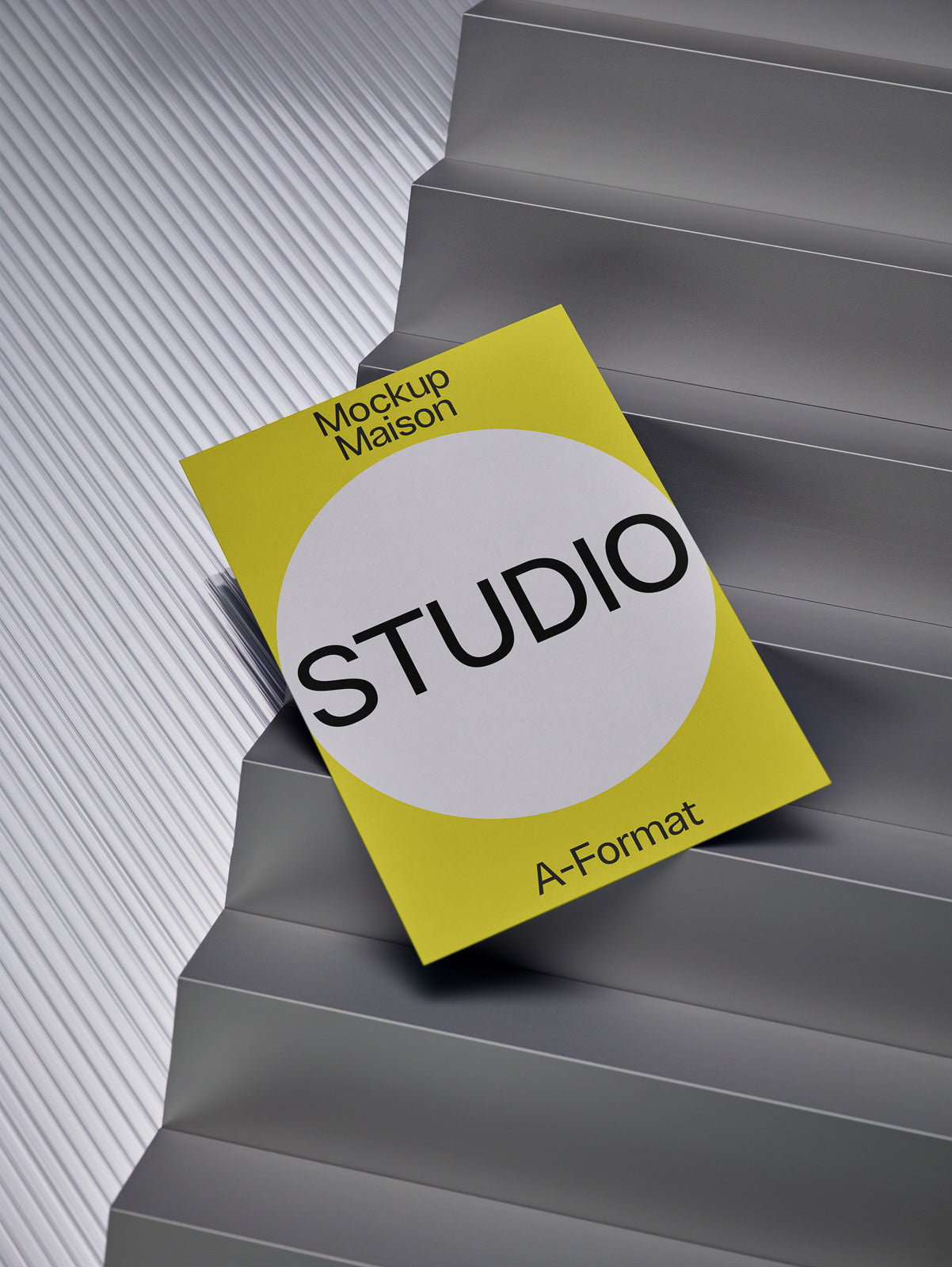 PSD mockup of a yellow and white Studio booklet on stepped metallic surface.