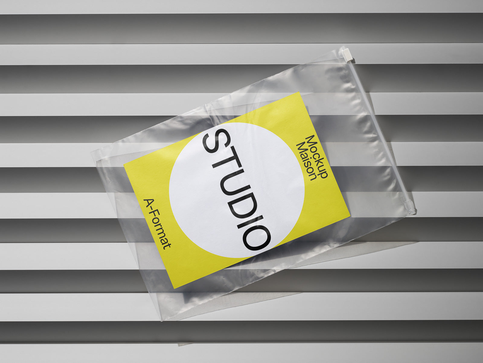 PSD mockup of a plastic ziplock bag displaying a yellow and white paper labeled "Studio A-Format" on a gray striped background.