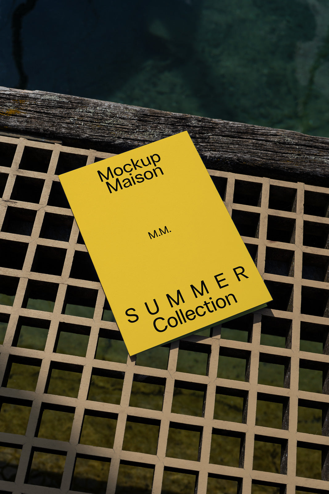PSD mockup of a yellow card labeled "Mockup Maison Summer Collection" placed on a lattice surface near a wooden edge, with water visible below.