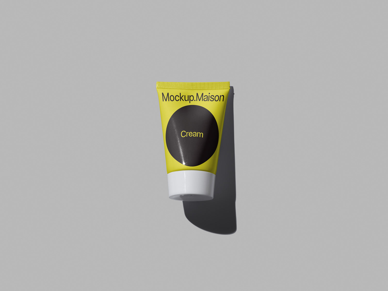 PSD mockup of a yellow cream tube labeled "Mockup Maison" against a gray background, casting a soft shadow to the right.