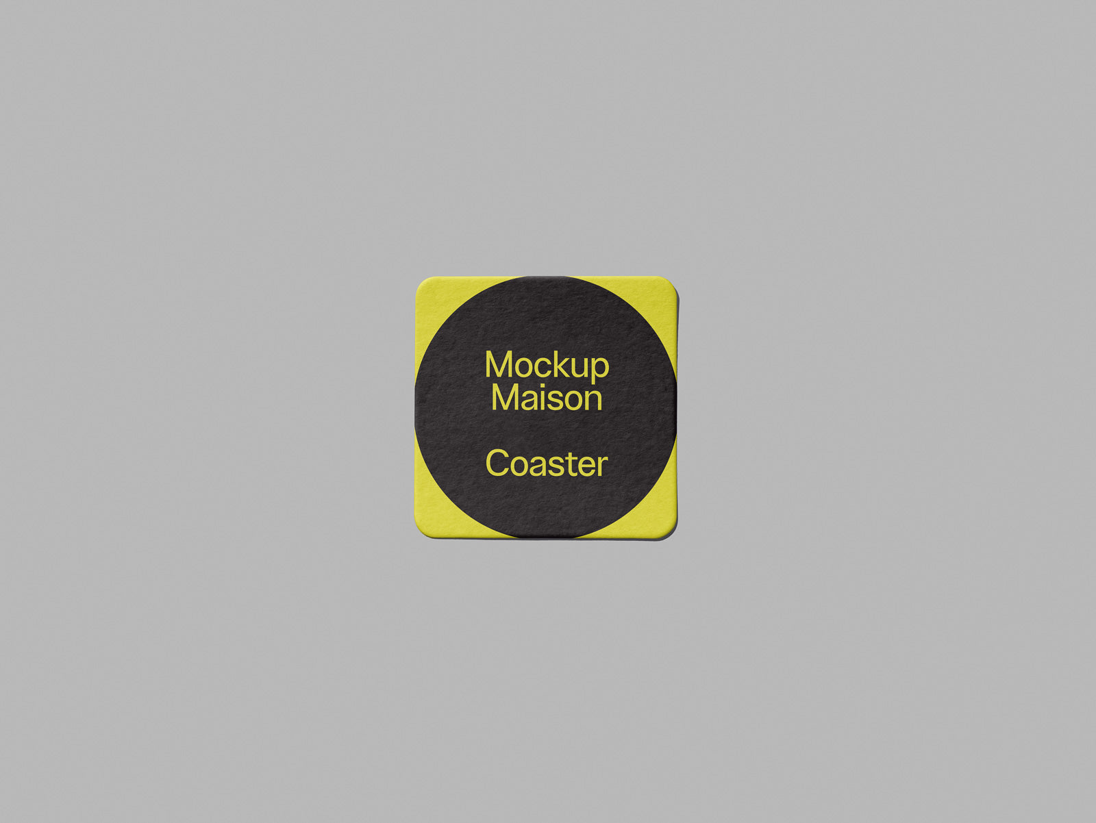 PSD mockup of a square yellow coaster with a central black circle displaying the text "Mockup Maison Coaster." Subtle lighting on a gray background.