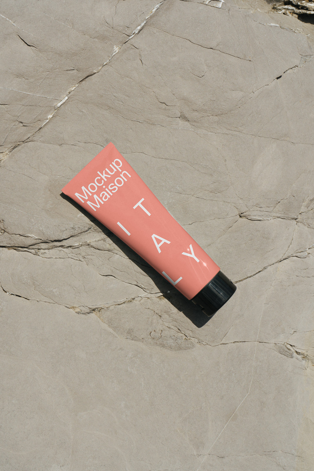 PSD mockup of a pink tube labeled "Mockup Maison" and "ITALY" on textured stone surface.
