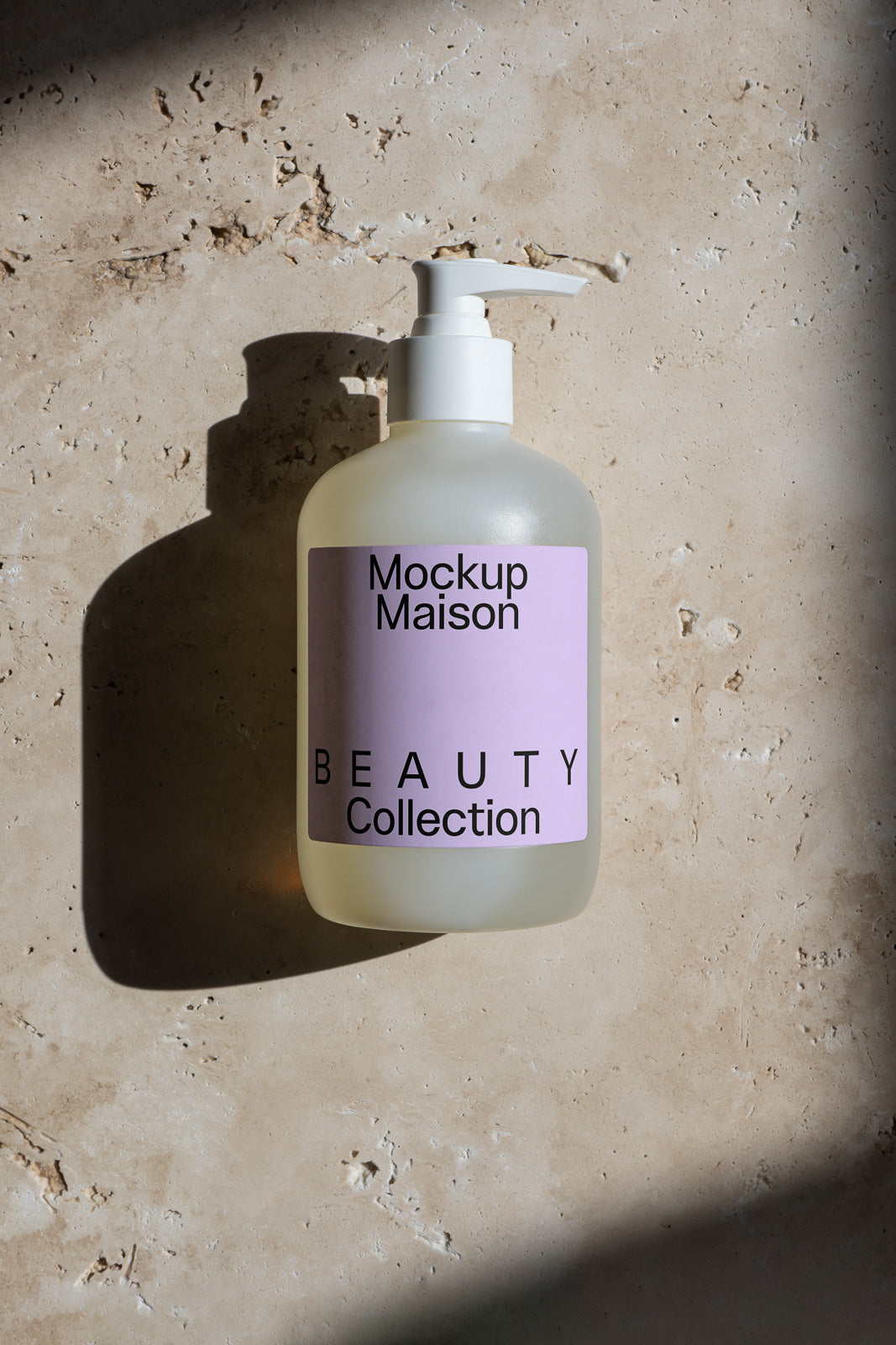 PSD mockup of a frosted pump bottle labeled "Mockup Maison Beauty Collection" on a textured stone background with shadow.
