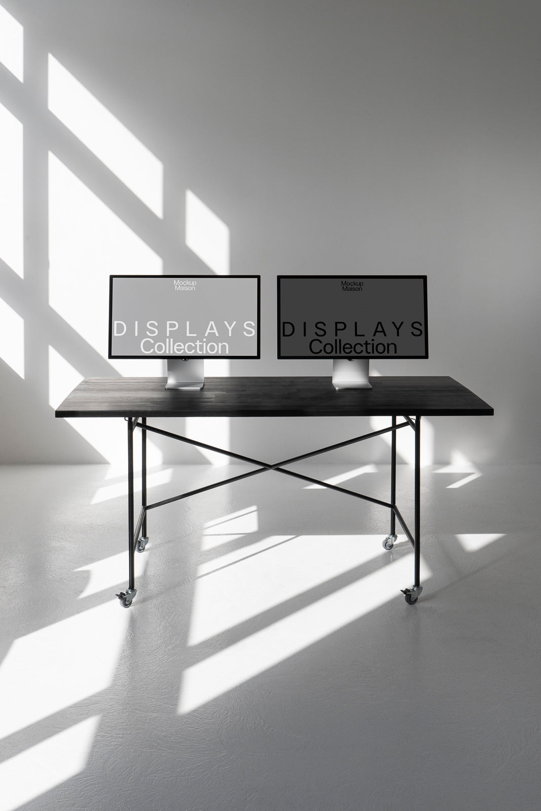 PSD mockup of two computer monitors on a black table with metal legs, set against a light-filled room with geometric shadows on the floor.