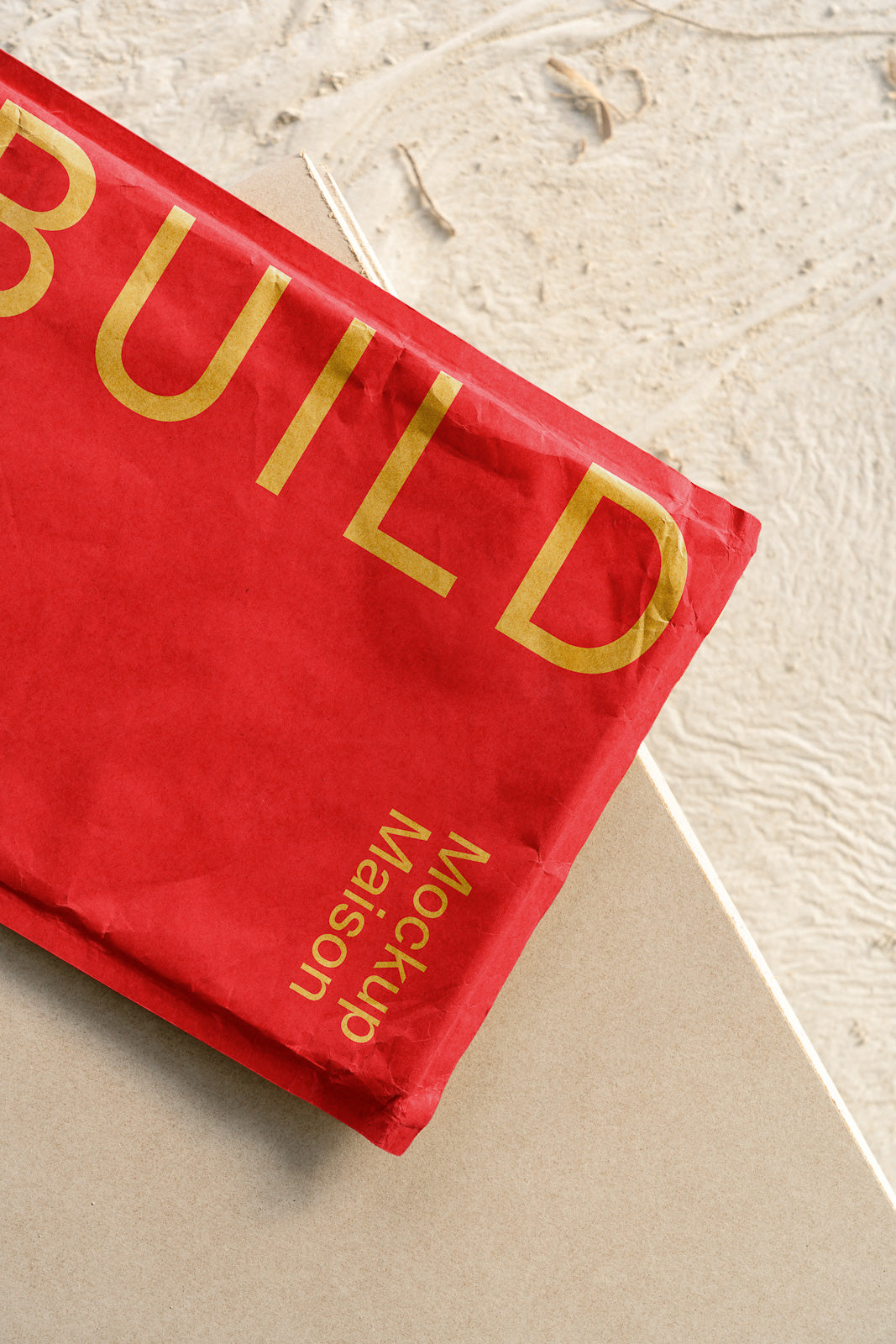 PSD mockup of a red envelope with gold text reading "BUILD" on a beige textured background.
