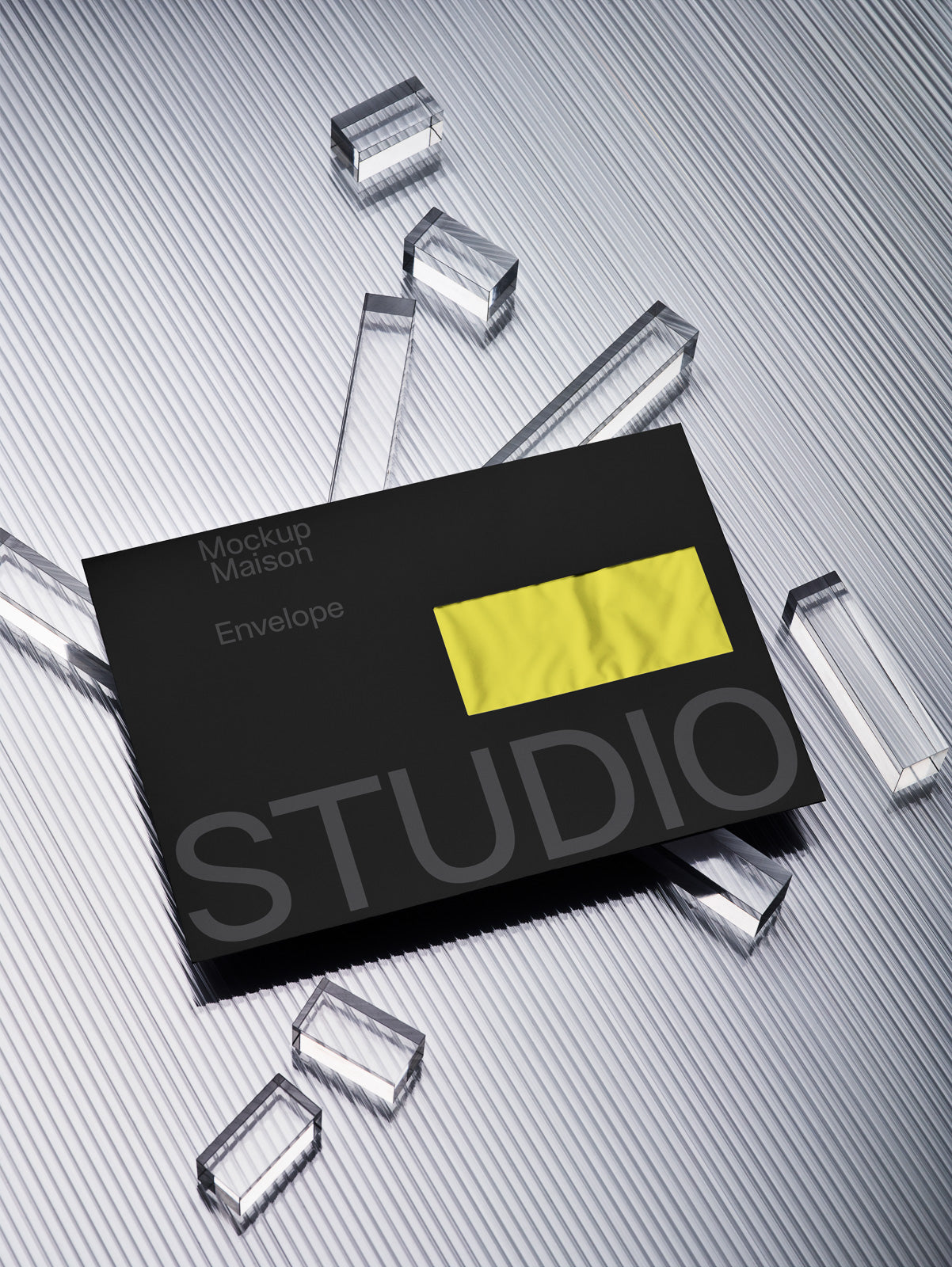 PSD mockup of a black envelope with bold gray "STUDIO" text, featuring a bright yellow rectangle, placed on a corrugated metallic surface with transparent acrylic blocks.