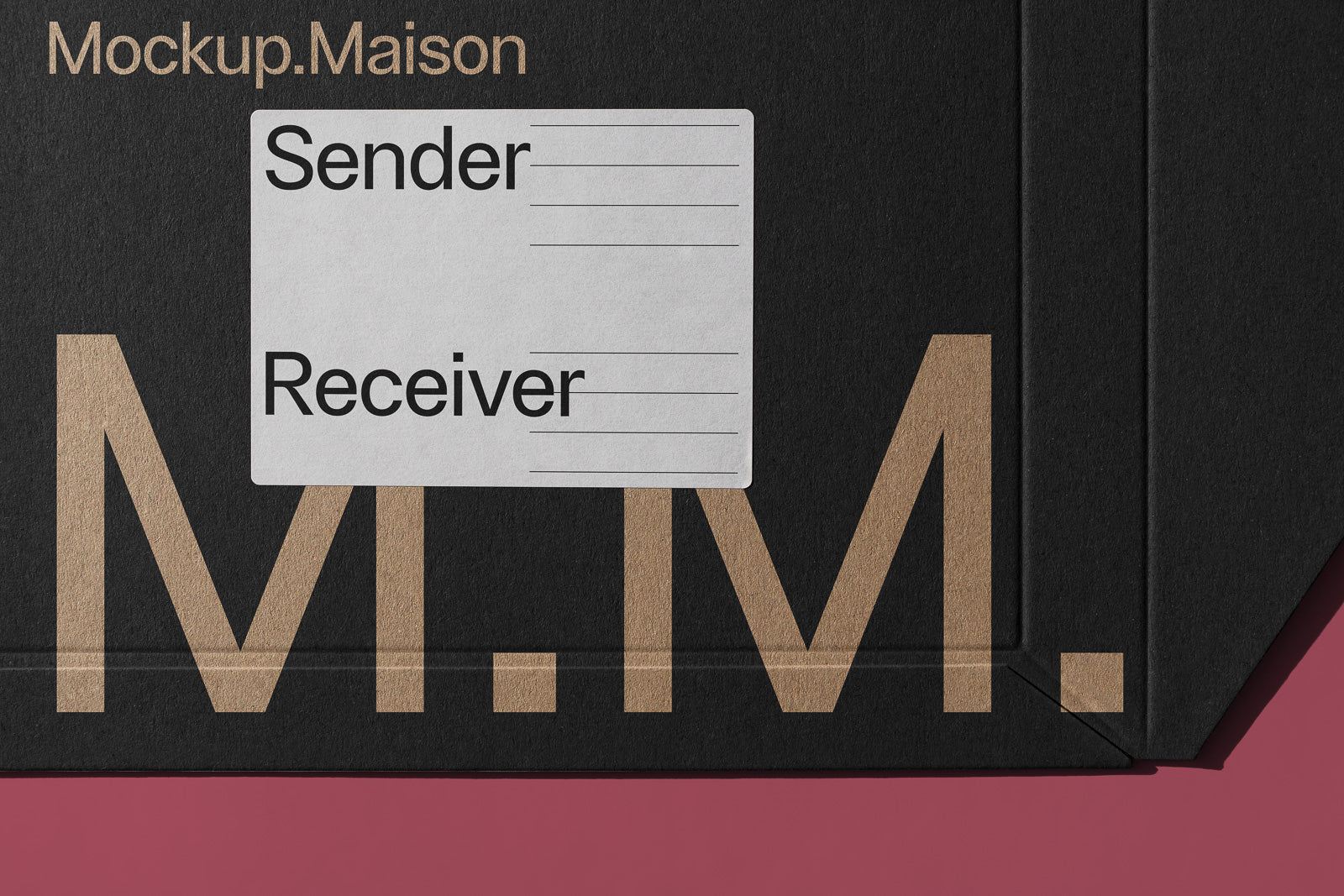 PSD mockup of a black cardboard box decorated with large beige initials "M.M." and a label for sender and receiver information, resting on a pink surface.