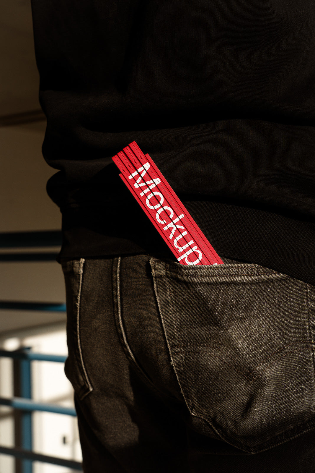 PSD mockup of a red mockup card peeking out of the back pocket of black denim jeans, with a focus on the textures and colors.