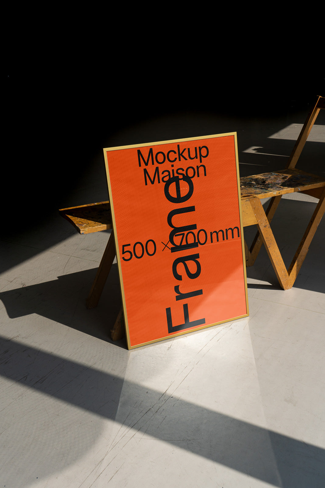 PSD mockup of a standing frame with "Mockup Maison 500 x 700 mm" text on an orange background, placed against a wooden structure in a sunlit space.
