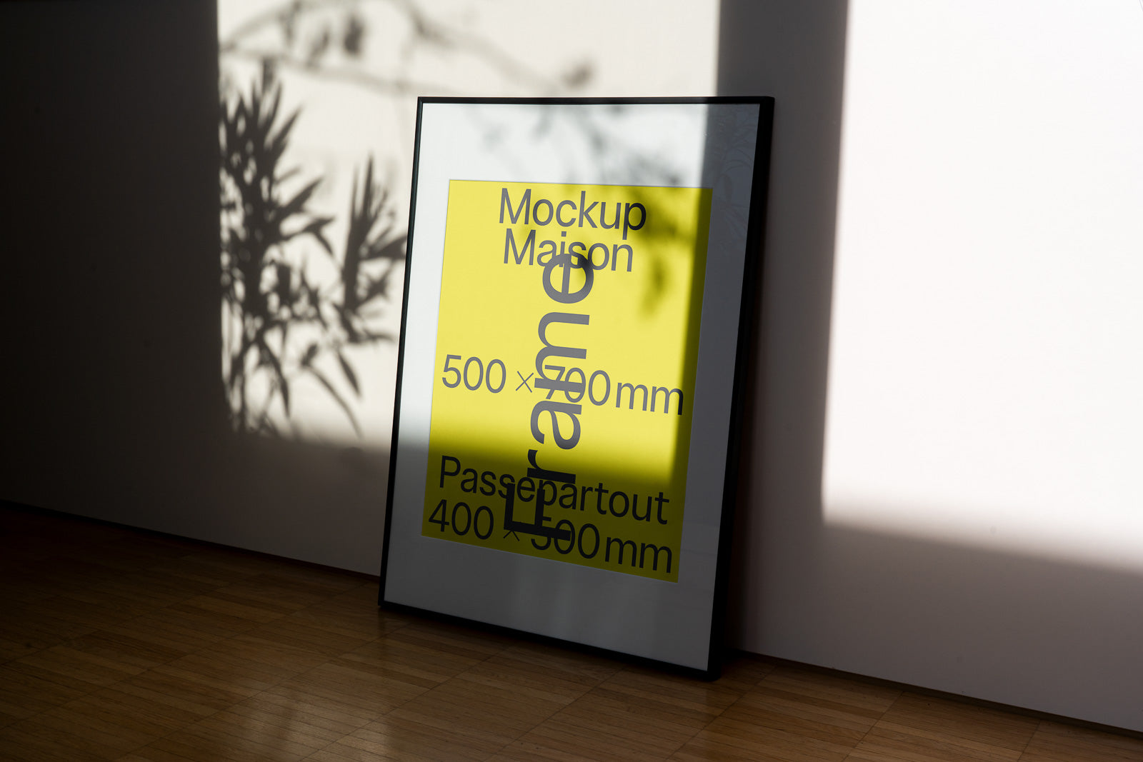 PSD mockup of a framed poster leaning against a wall, displaying dimensions and text on a yellow background with shadow effects.
