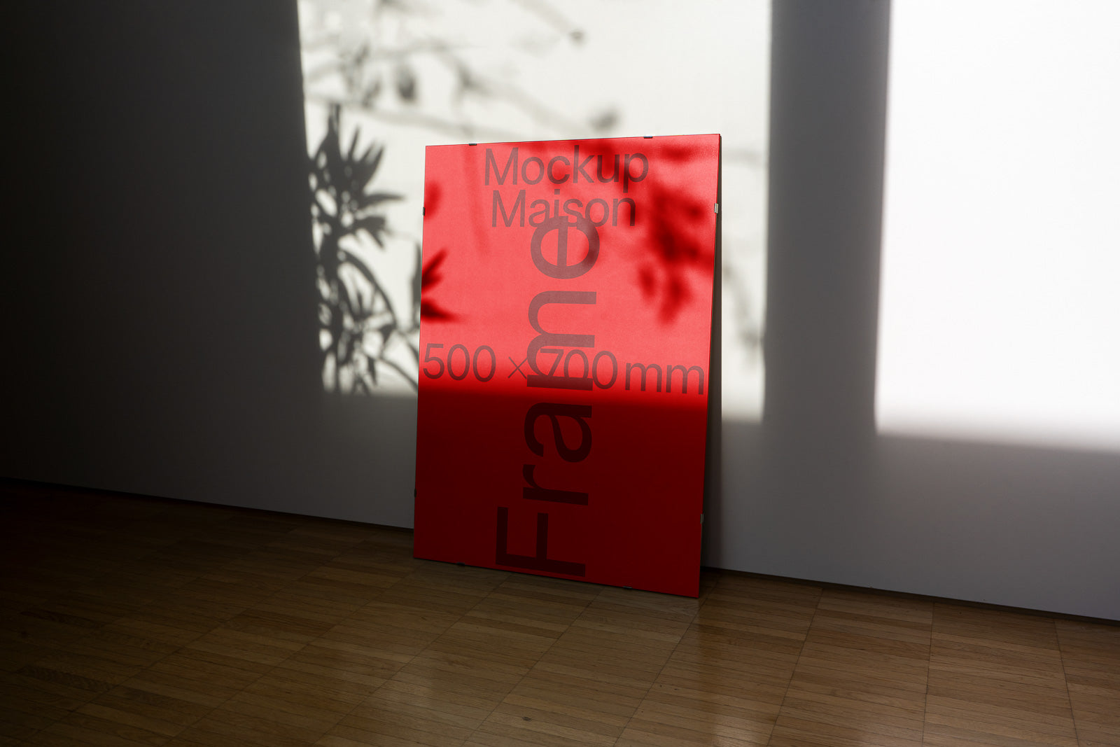 PSD mockup of a red panel with the text "Mockup Maison 500 x 700 mm" leaning against a white wall, casting plant shadows on the surface.