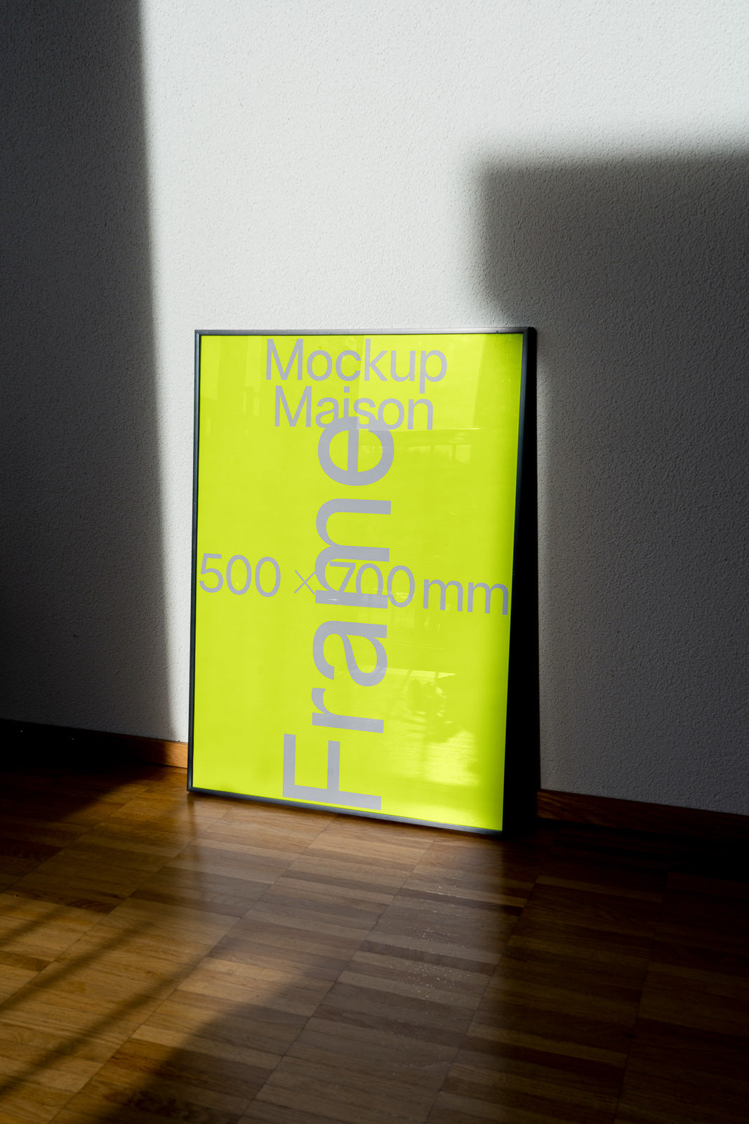 PSD mockup of a vertical frame with a neon green backdrop, leaning against a light gray wall on a wooden floor, partially in shadow.