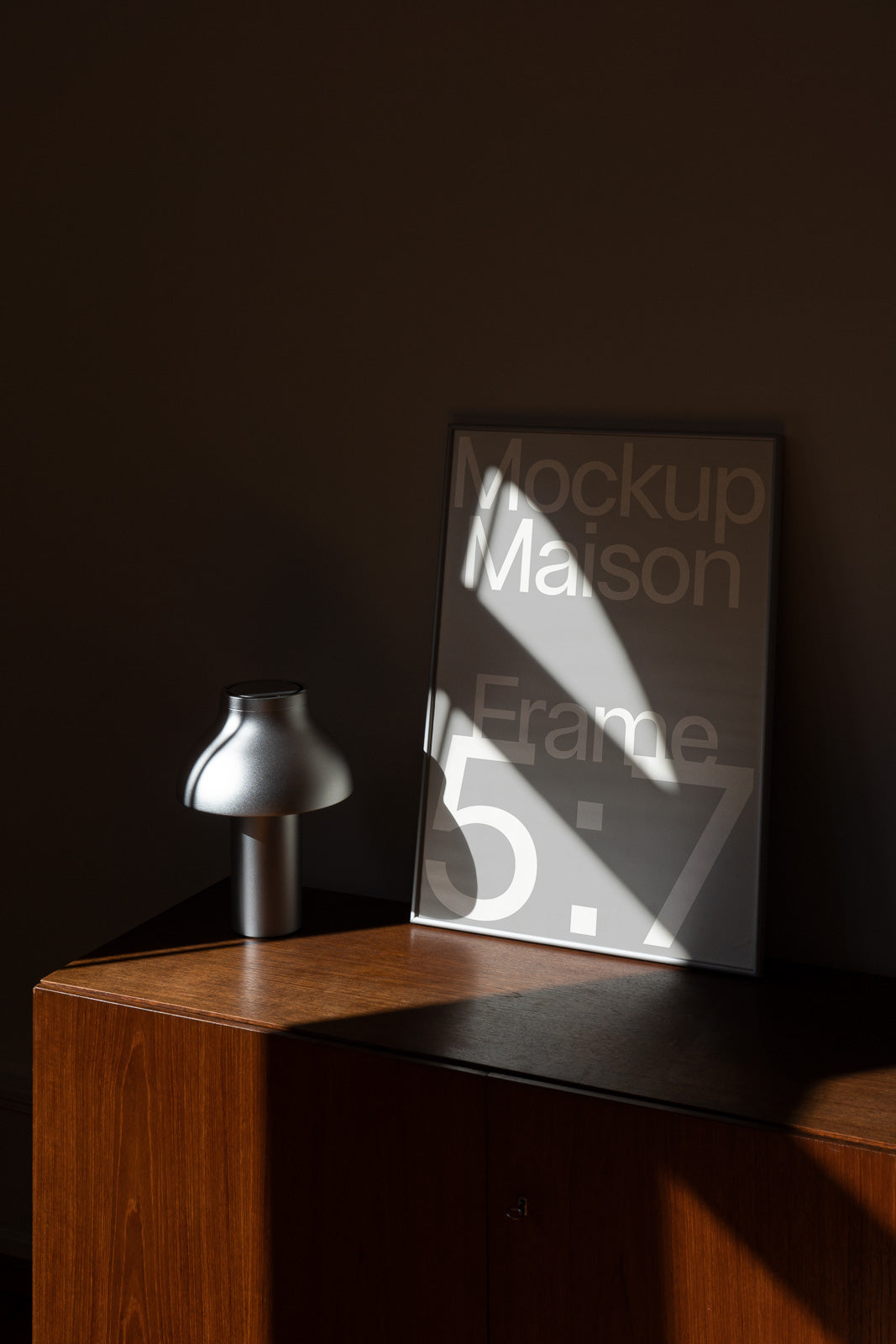 PSD mockup of a stylish, sleek metallic table lamp beside a vertically positioned 5:7 frame with bold text in soft lighting.