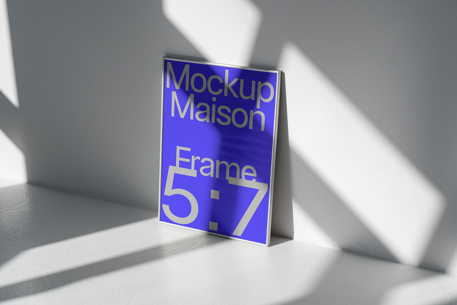 PSD mockup of a blue and white 5:7 frame leaning against a wall, with shadows casting across the surface.