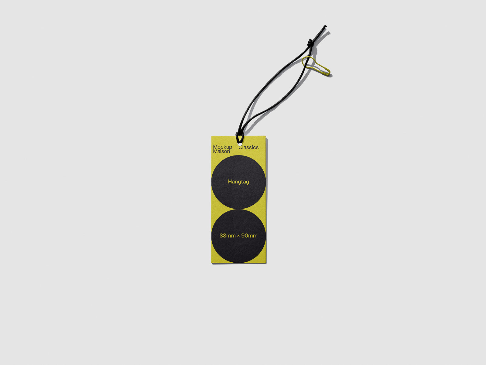 PSD mockup of a rectangular hangtag with a black string, featuring two black circles on a yellow background labeled with text, “Mockup Maison Classics” and “38mm x 50mm.”