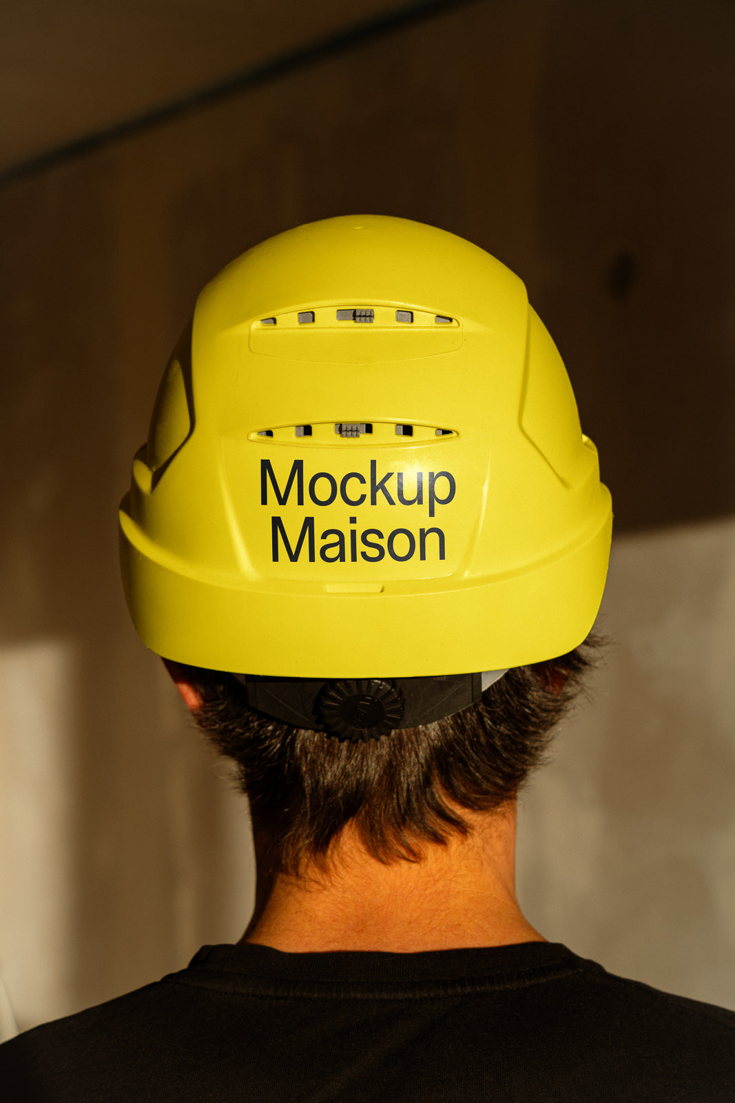PSD mockup of a yellow hard hat with "Mockup Maison" printed on the back, worn by an individual against a plain background.