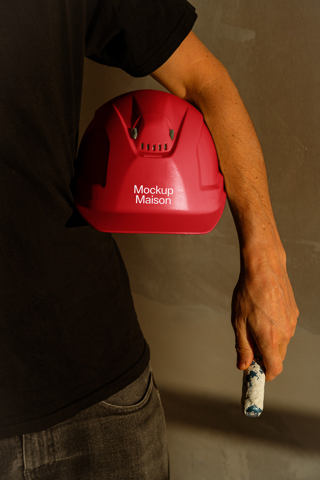 PSD mockup of a person holding a red hard hat with "Mockup Maison" text, illustrating construction or safety themes, against a neutral background.